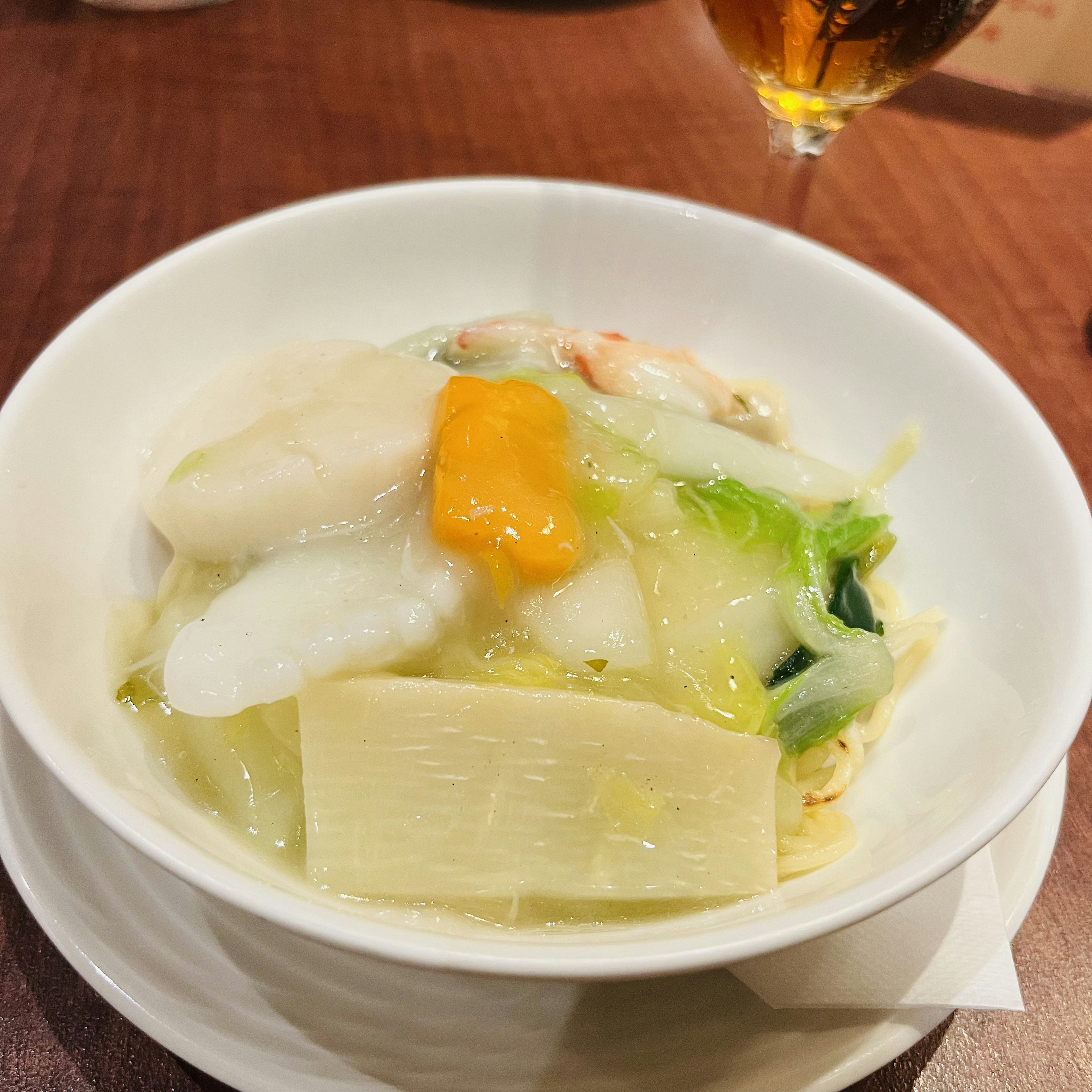 白いボウルに盛られた野菜と魚介類の料理、緑色の野菜とオレンジ色のウニが特徴的