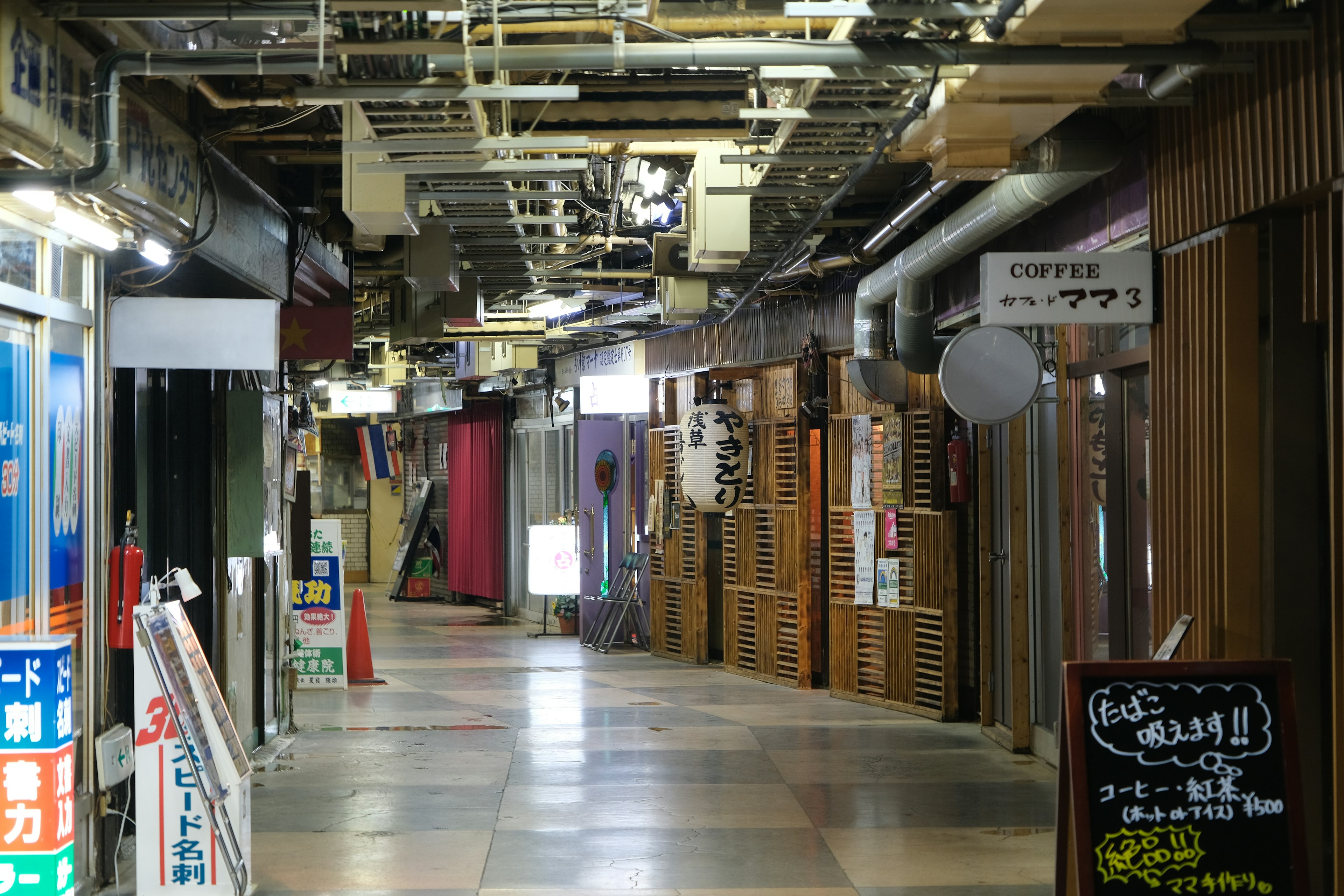 Lorong komersial sempit dengan berbagai toko dan papan nama