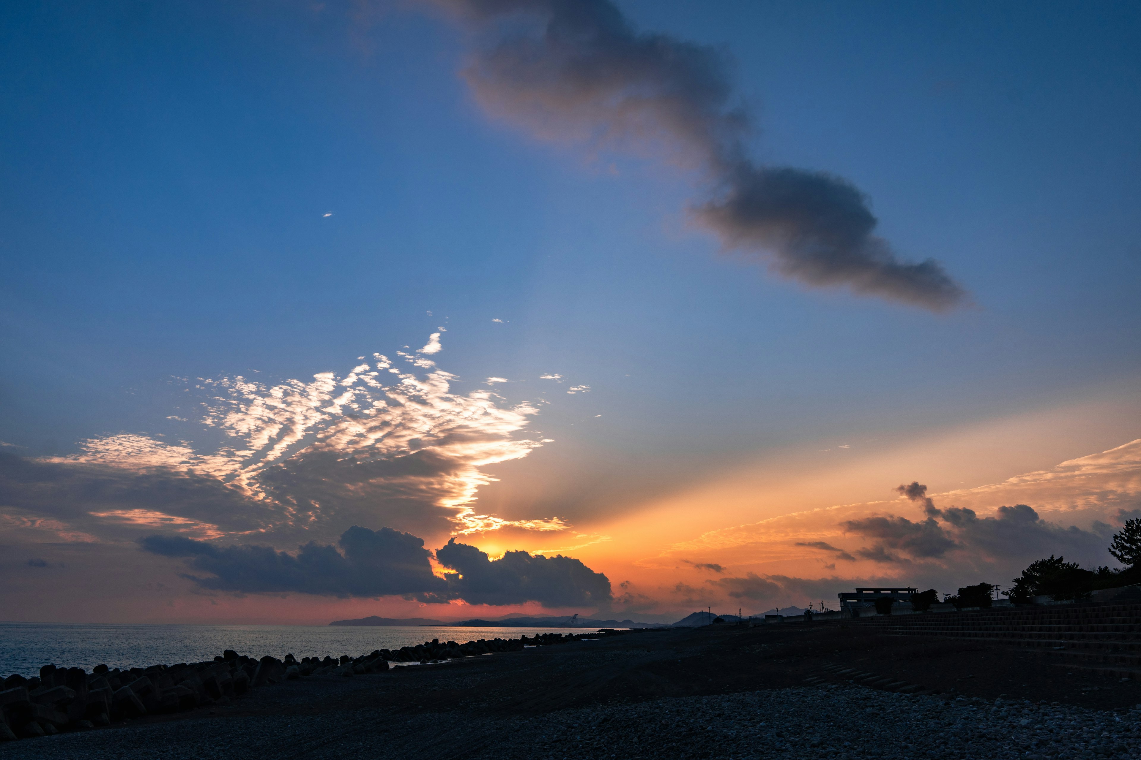 美しい夕焼けの空と雲のシルエット海岸線が見える