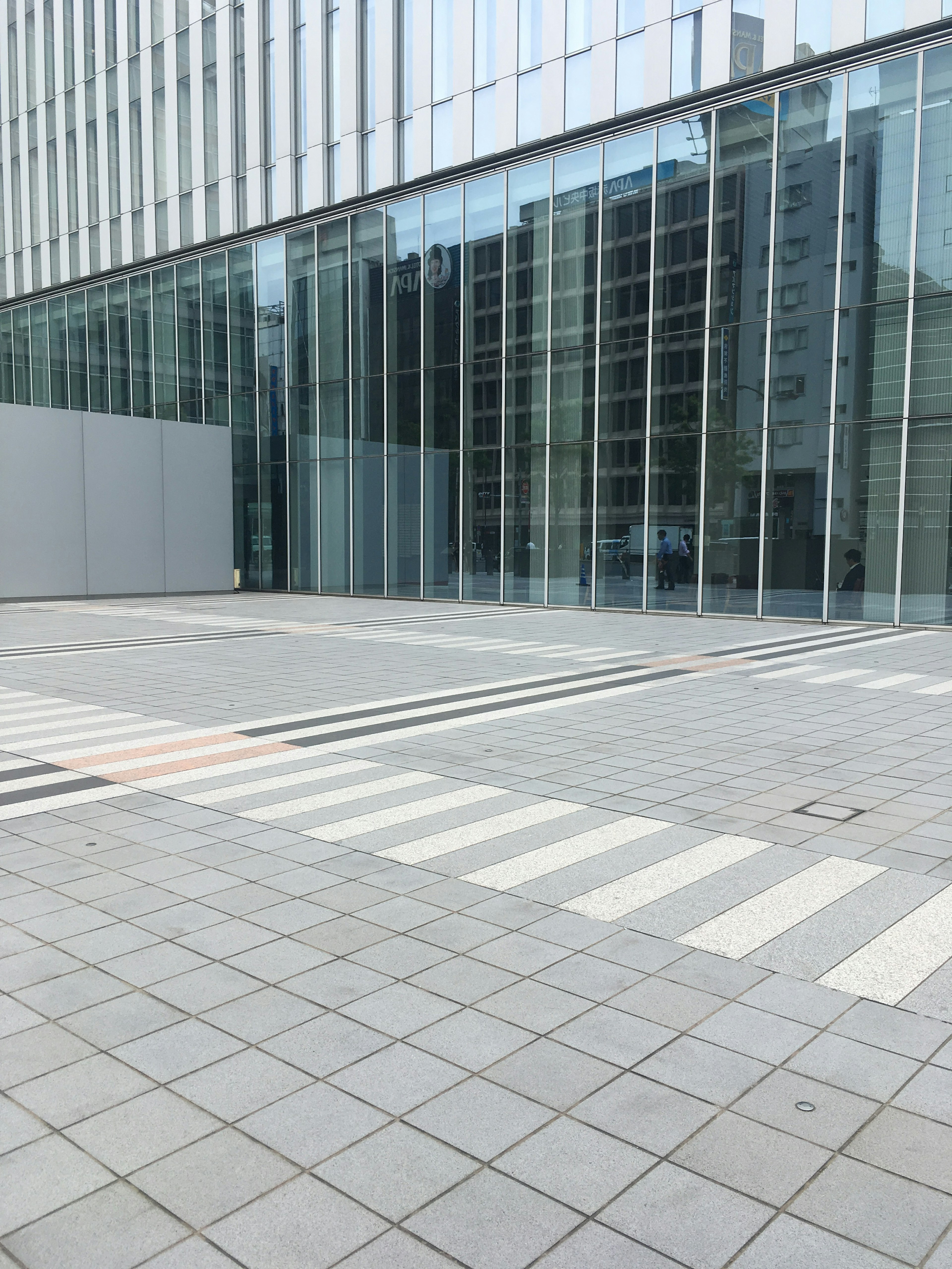 Modern building with glass facade and tiled pavement