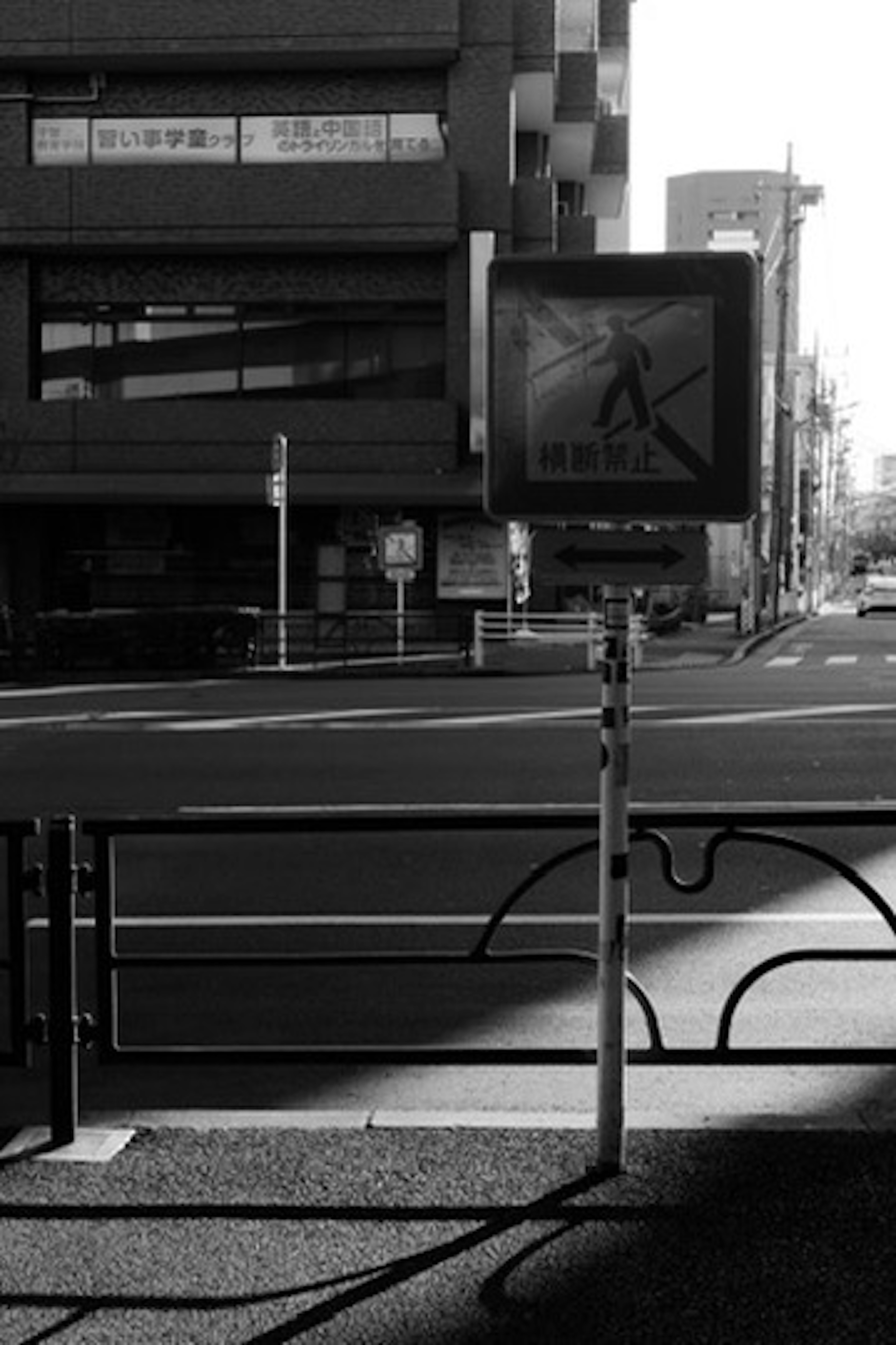 Black and white street corner with a pedestrian signal and buildings