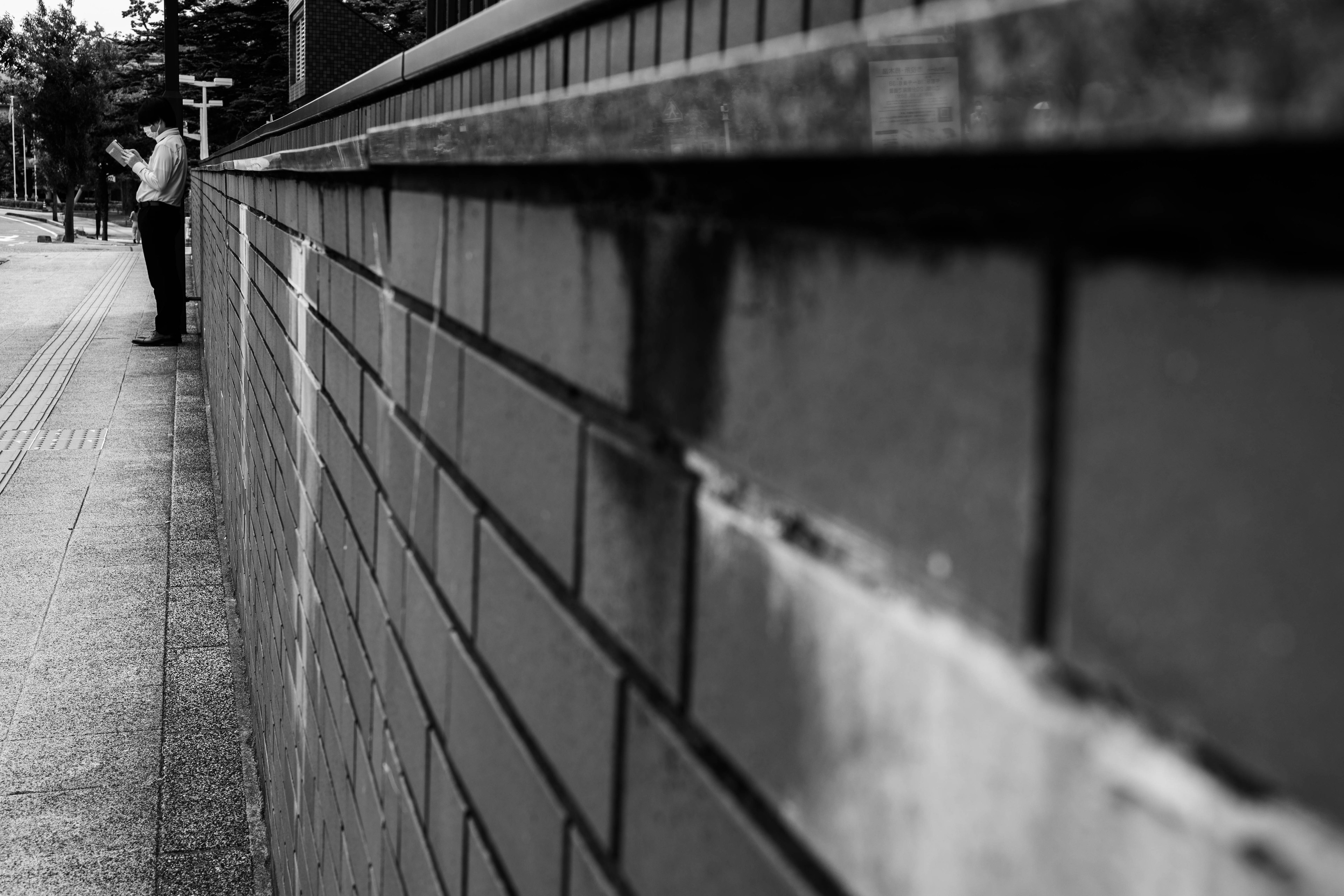 Close-up of a textured brick wall with a person standing in the background