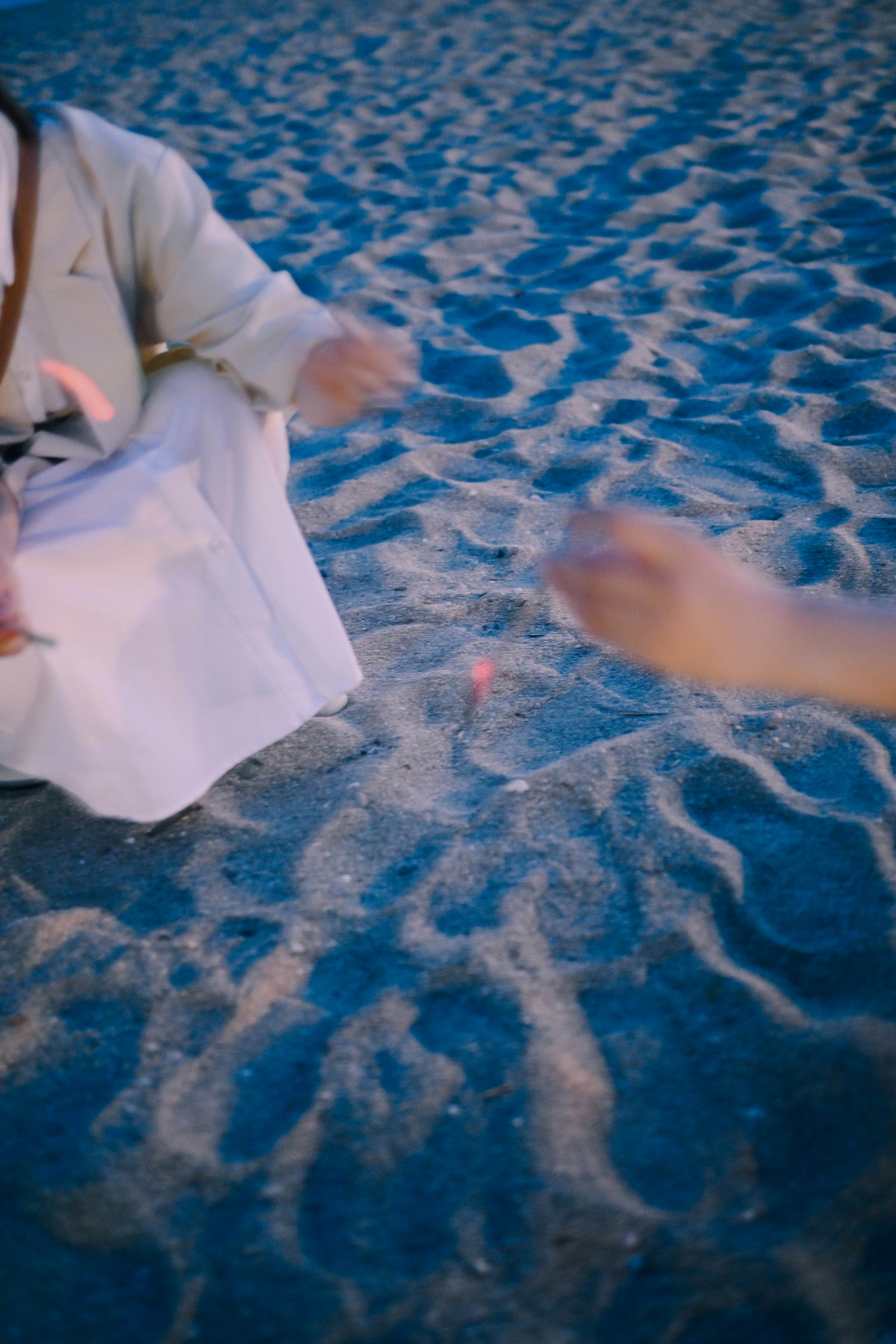 Deux mains jouant sur la plage avec une personne en vêtements blancs