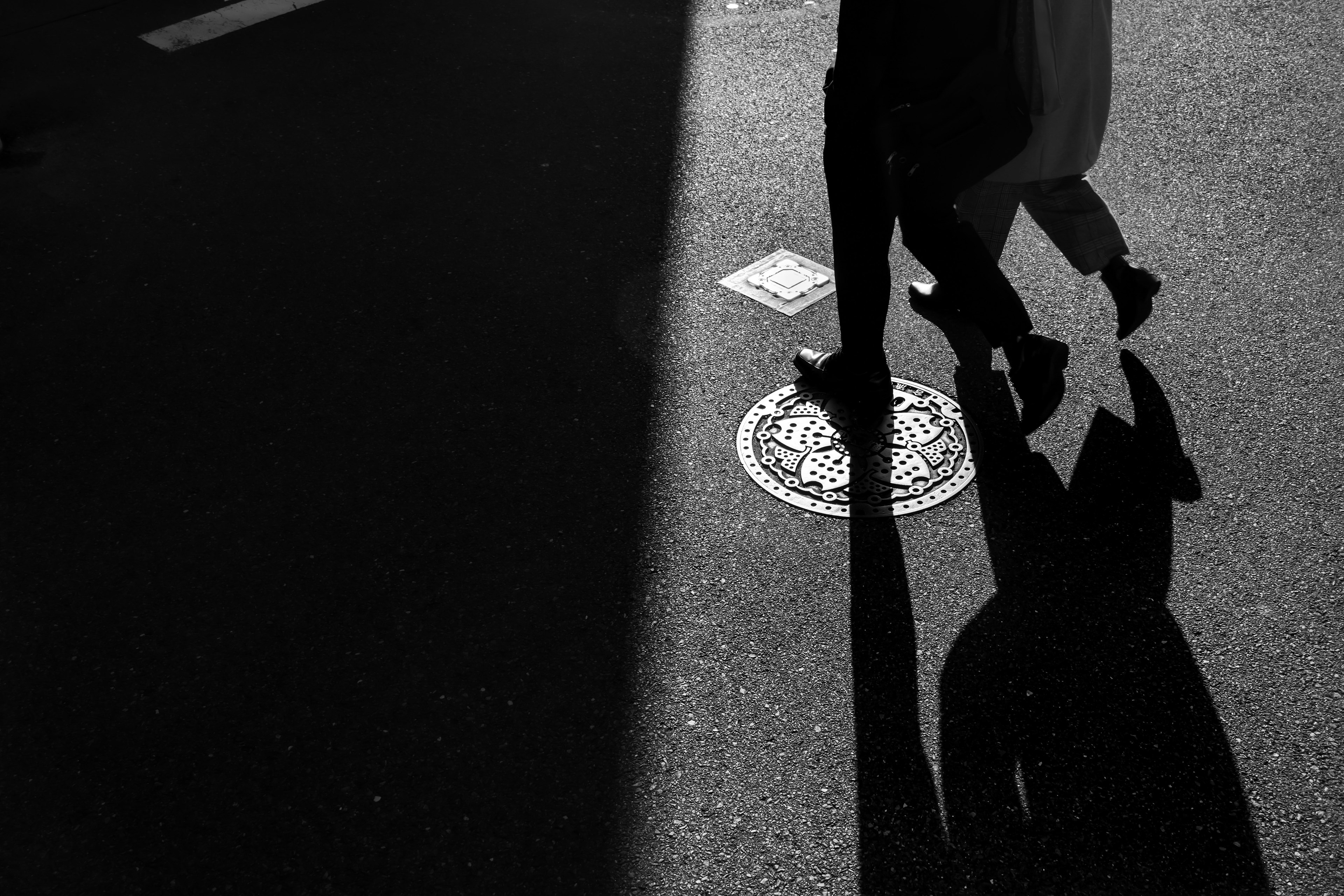 Silhouettes of people walking on the ground in black and white contrast