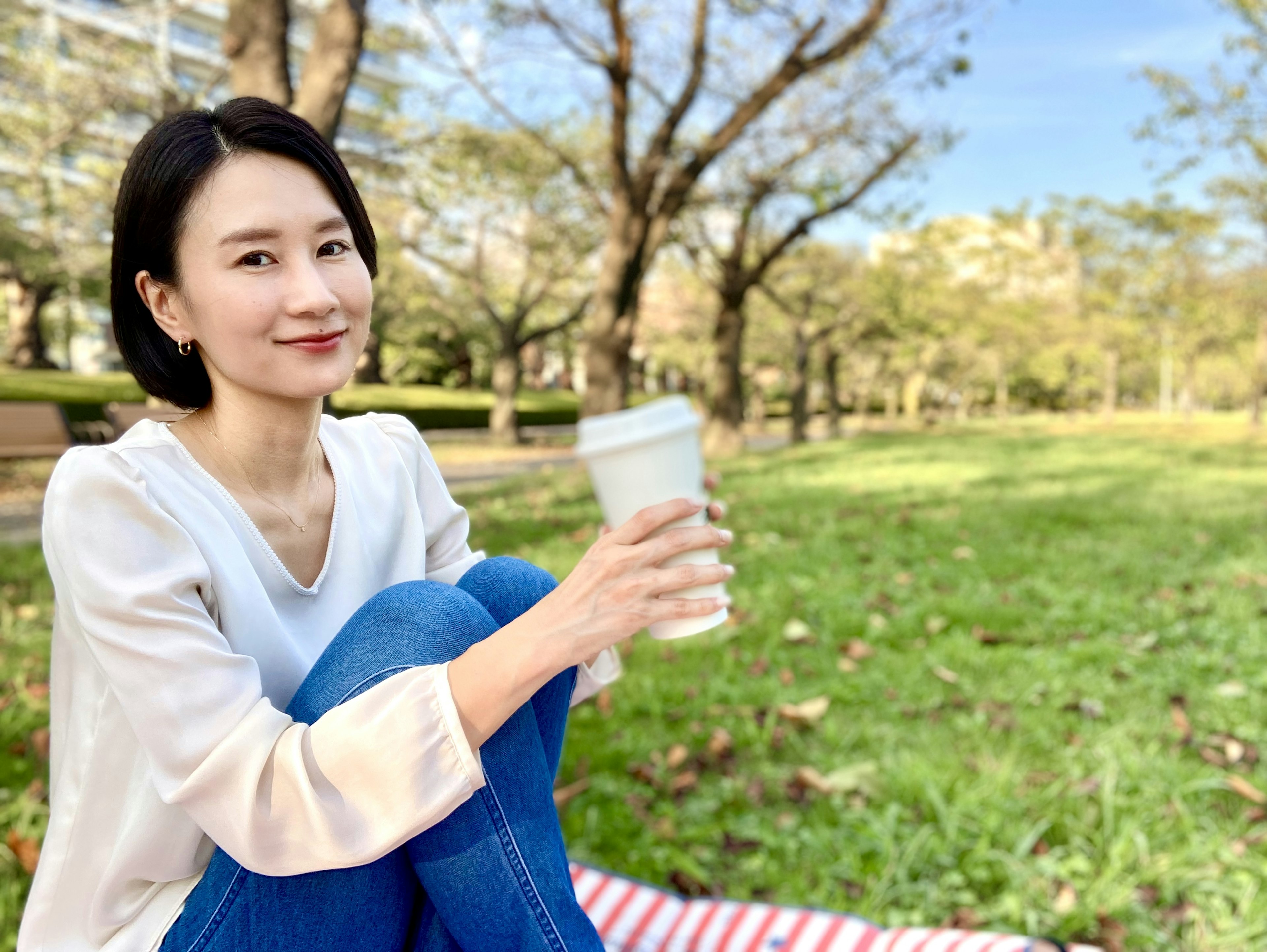 Porträt einer Frau, die Kaffee in einem Park hält