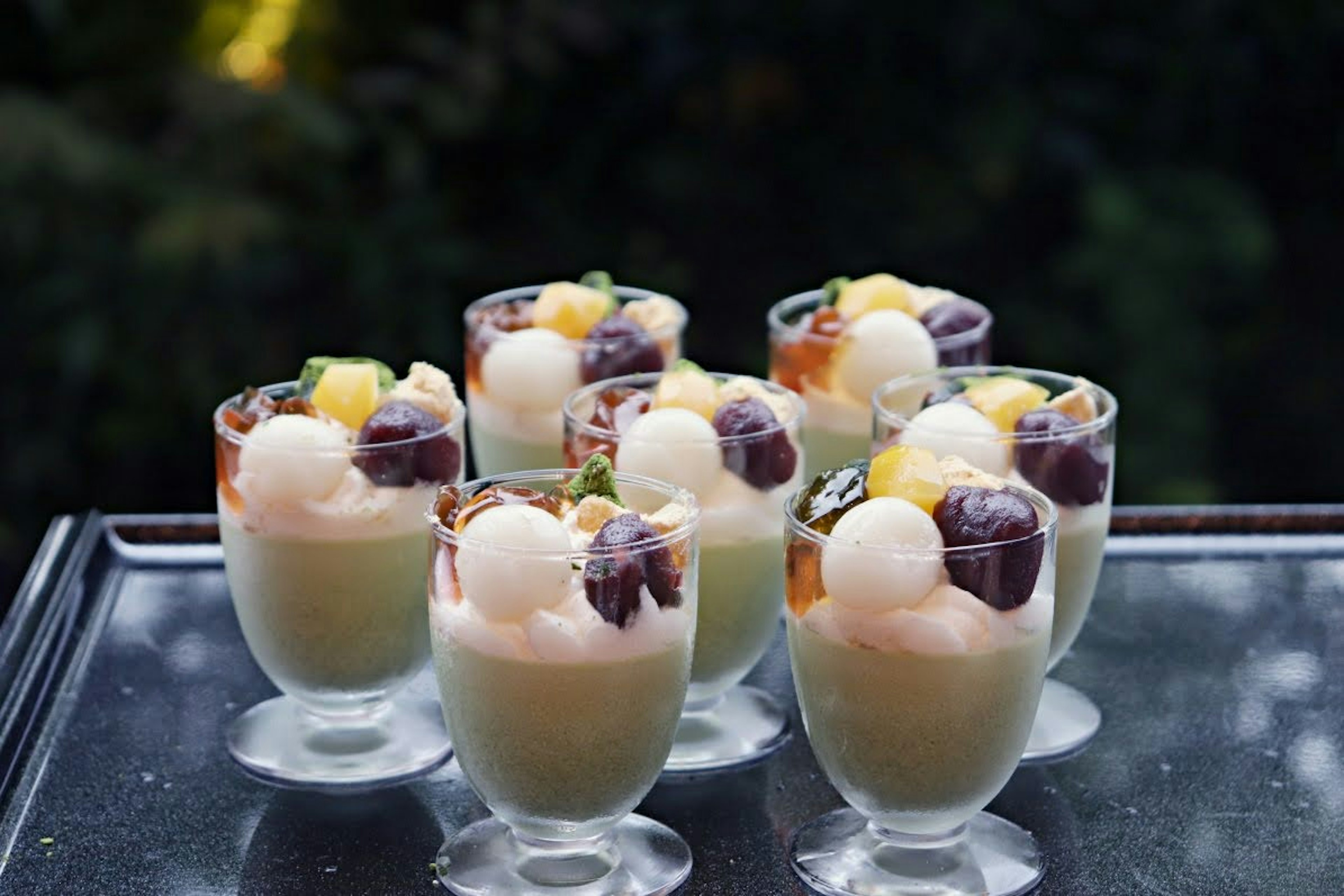 Colorful dessert cups topped with various fruits arranged on a table