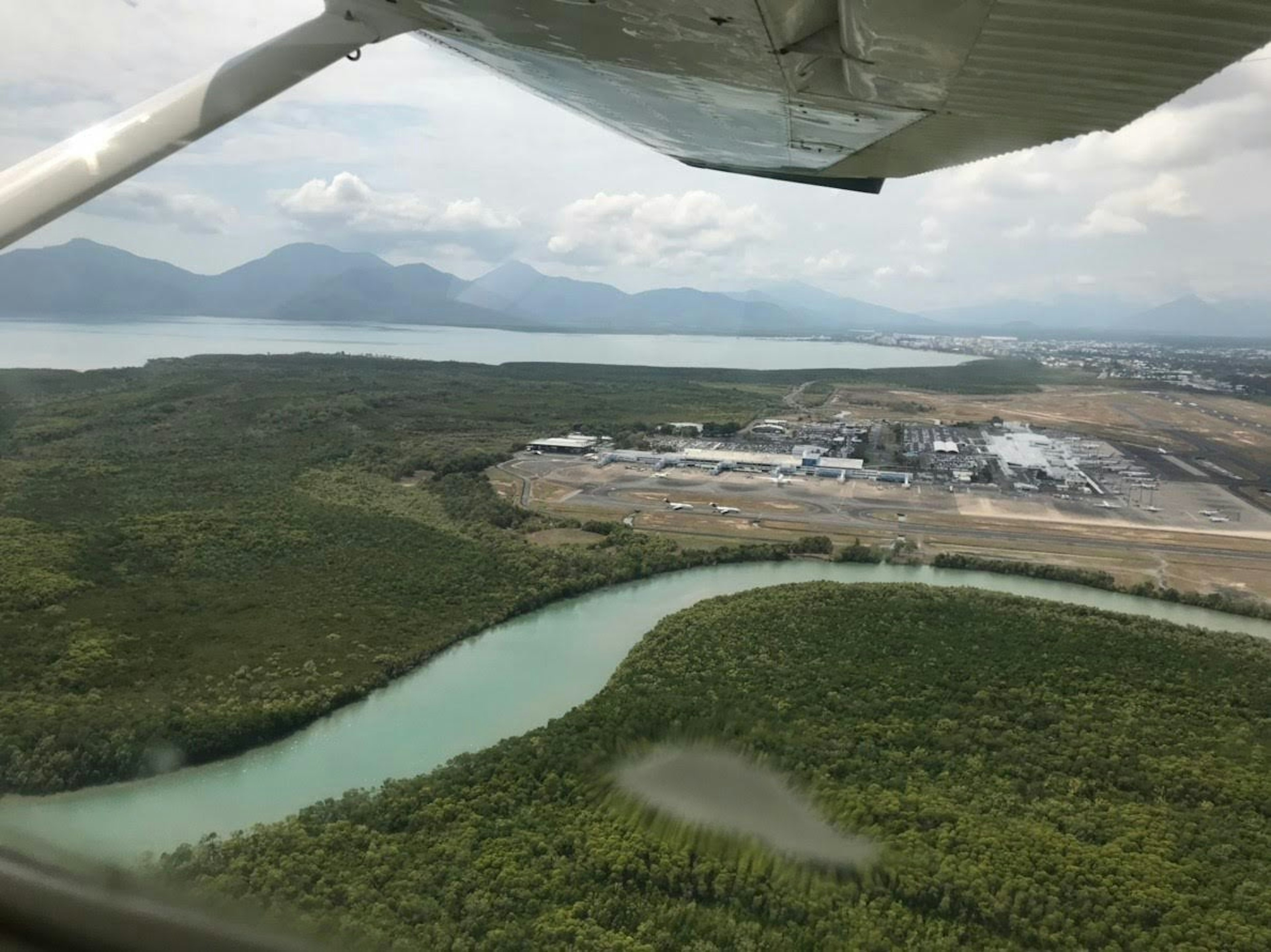 Pemandangan udara sungai berkelok-kelok dikelilingi pepohonan hijau dan pegunungan