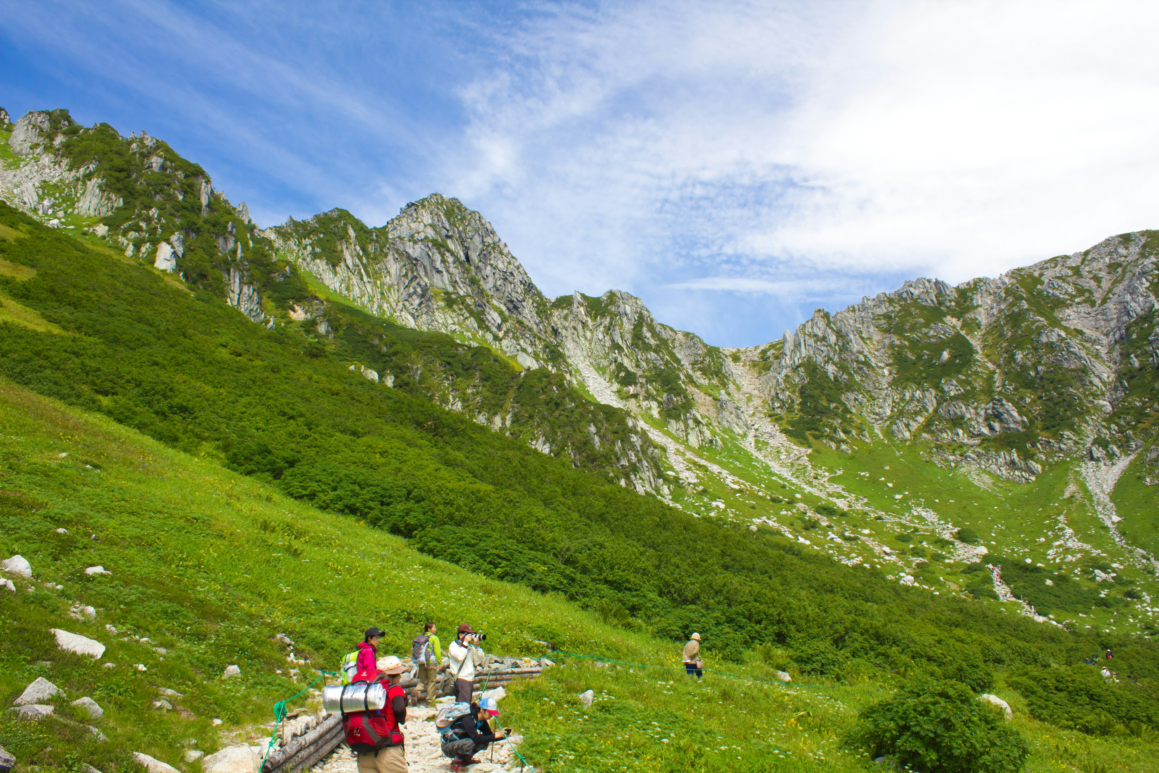 Hikers on a lush green mountain landscape