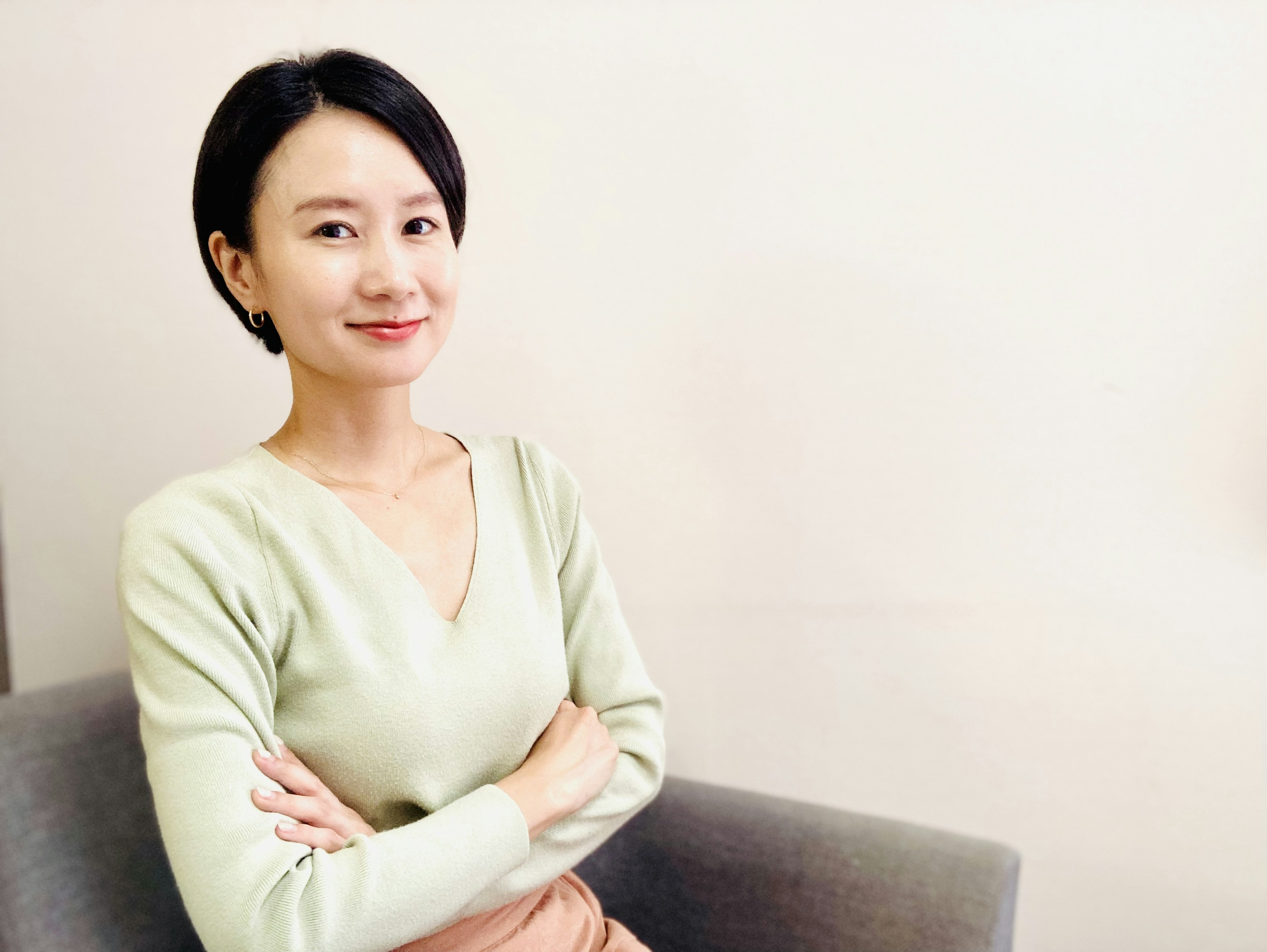 A woman sitting with arms crossed wearing a soft-colored sweater