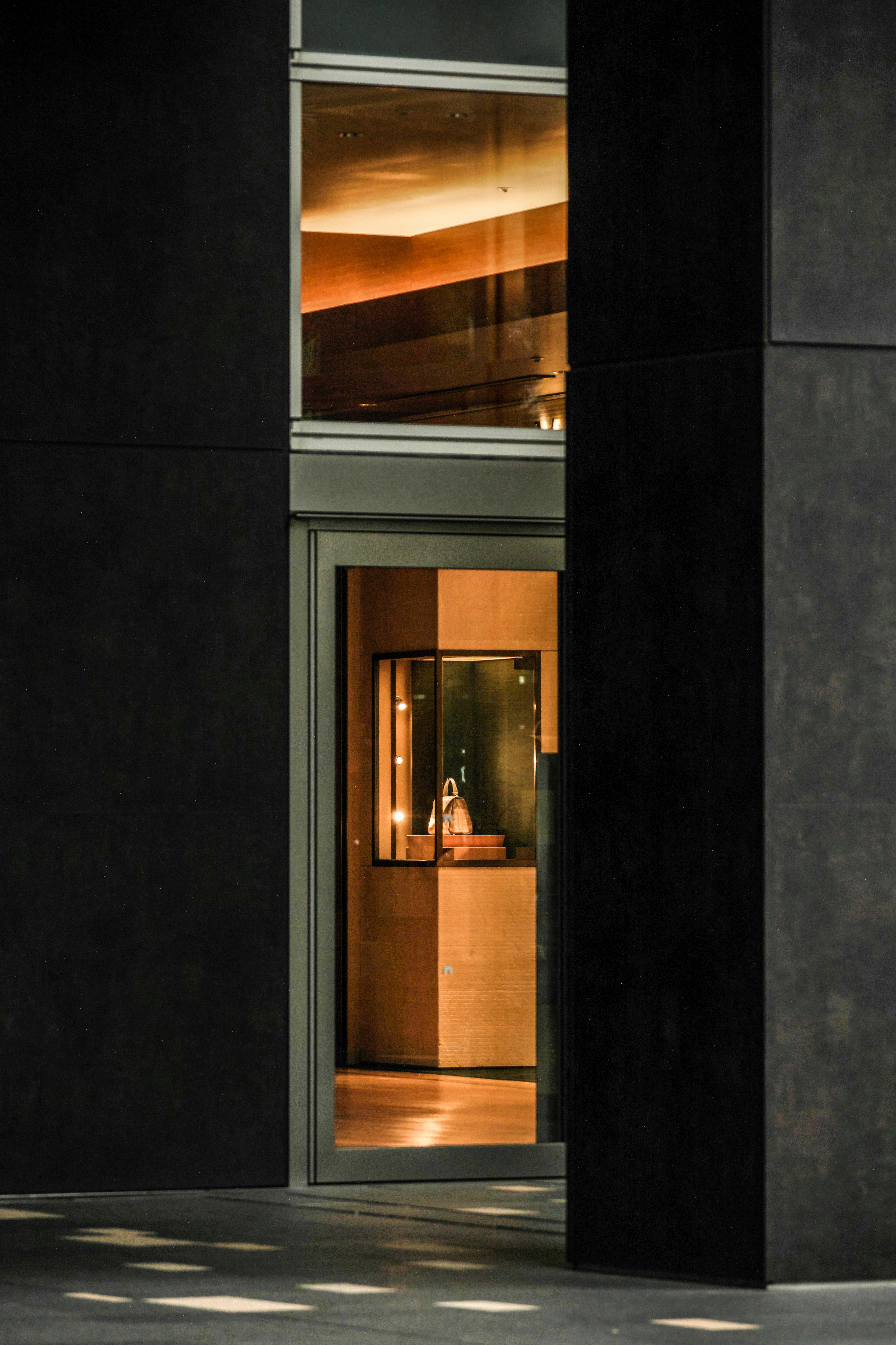 Dark building facade with a window revealing a bright interior space