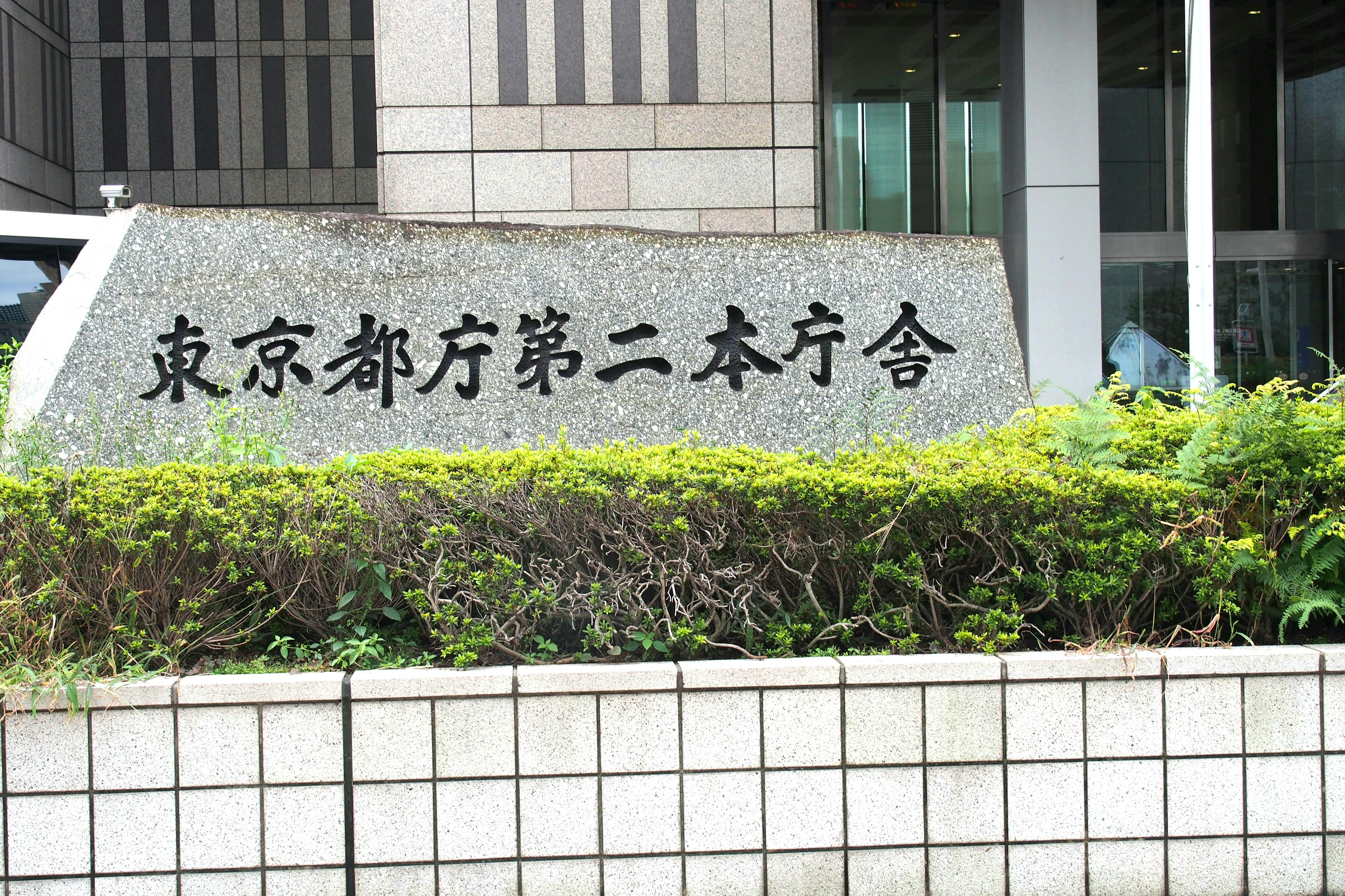 Monumento in pietra del secondo edificio principale del governo metropolitano di Tokyo con fogliame verde