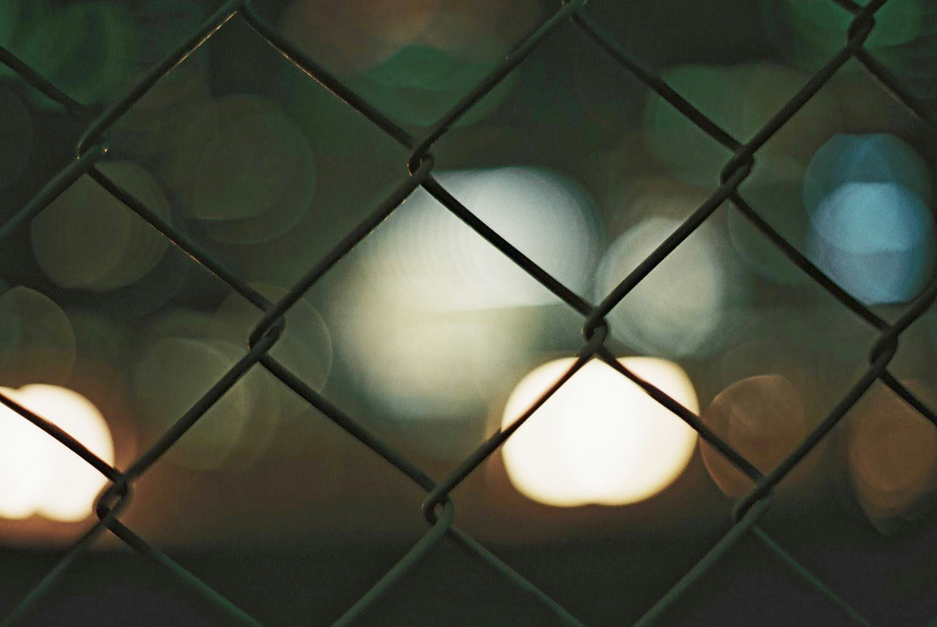 A wire mesh fence with a blurred background of lights