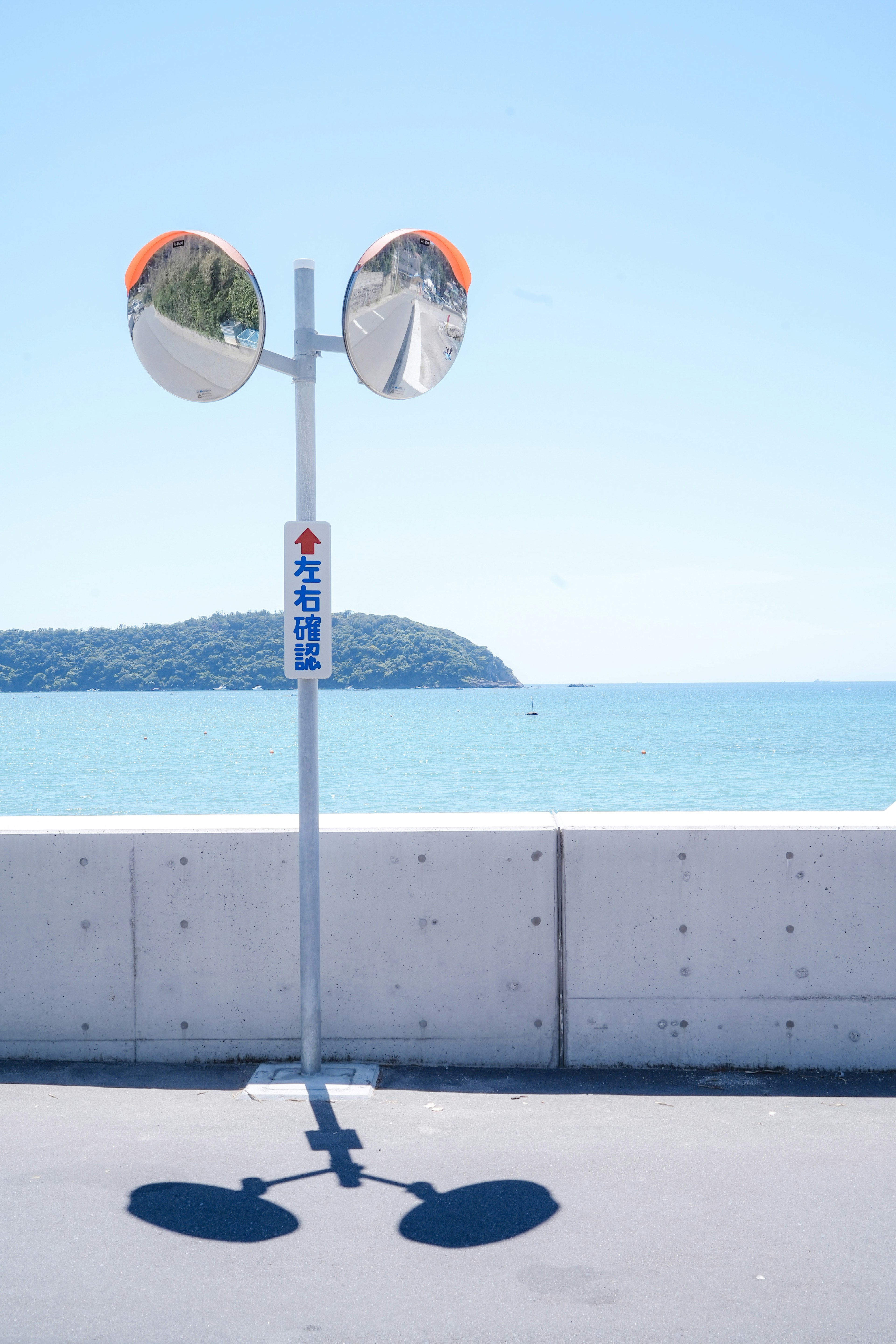 交通標誌，上面有兩面鏡子，背景是藍色海洋和一個島嶼