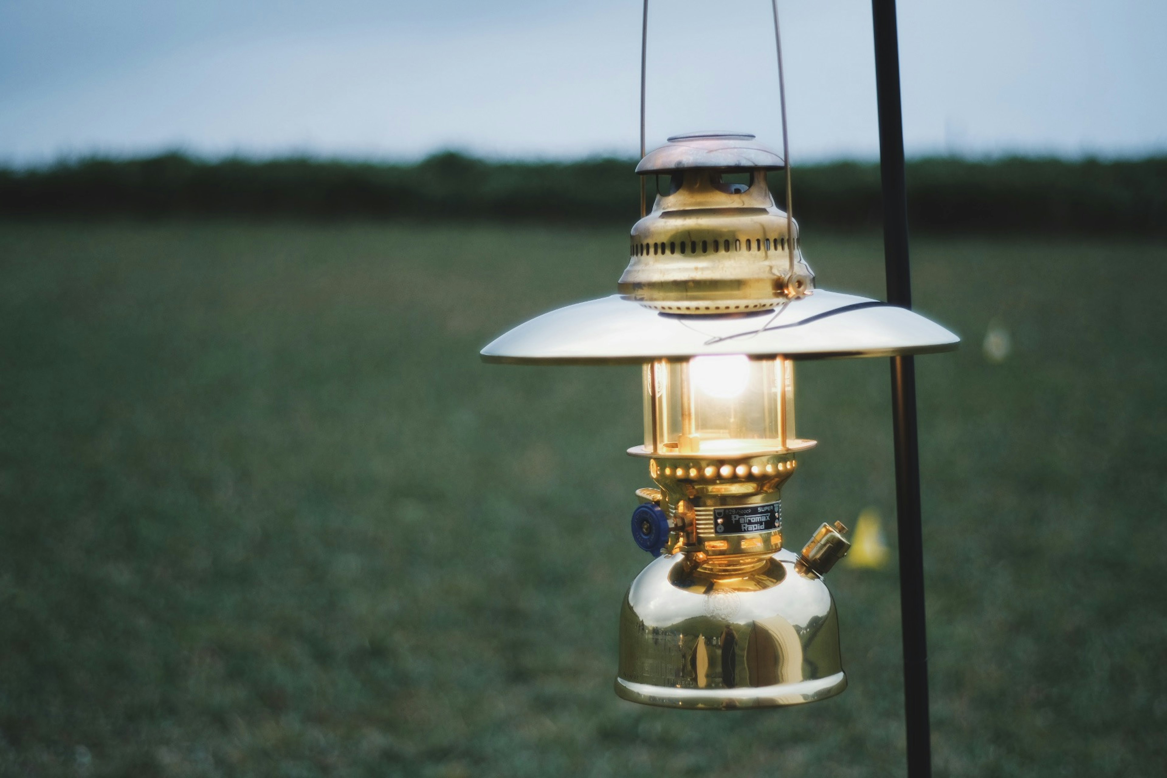 Golden lantern glowing in the dusk over a grassy field