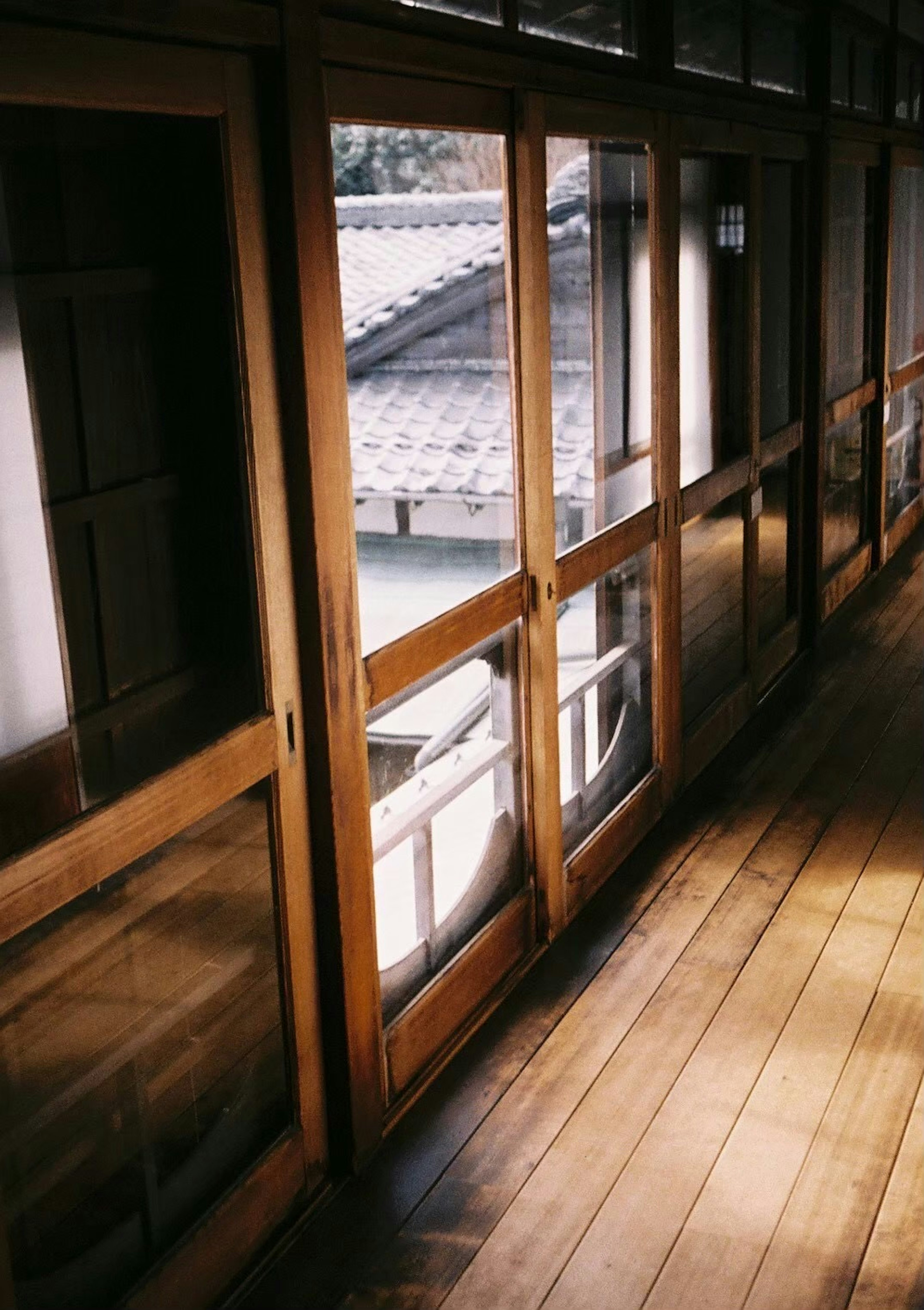 Pasillo de madera con grandes ventanas y suelo de madera luz que entra