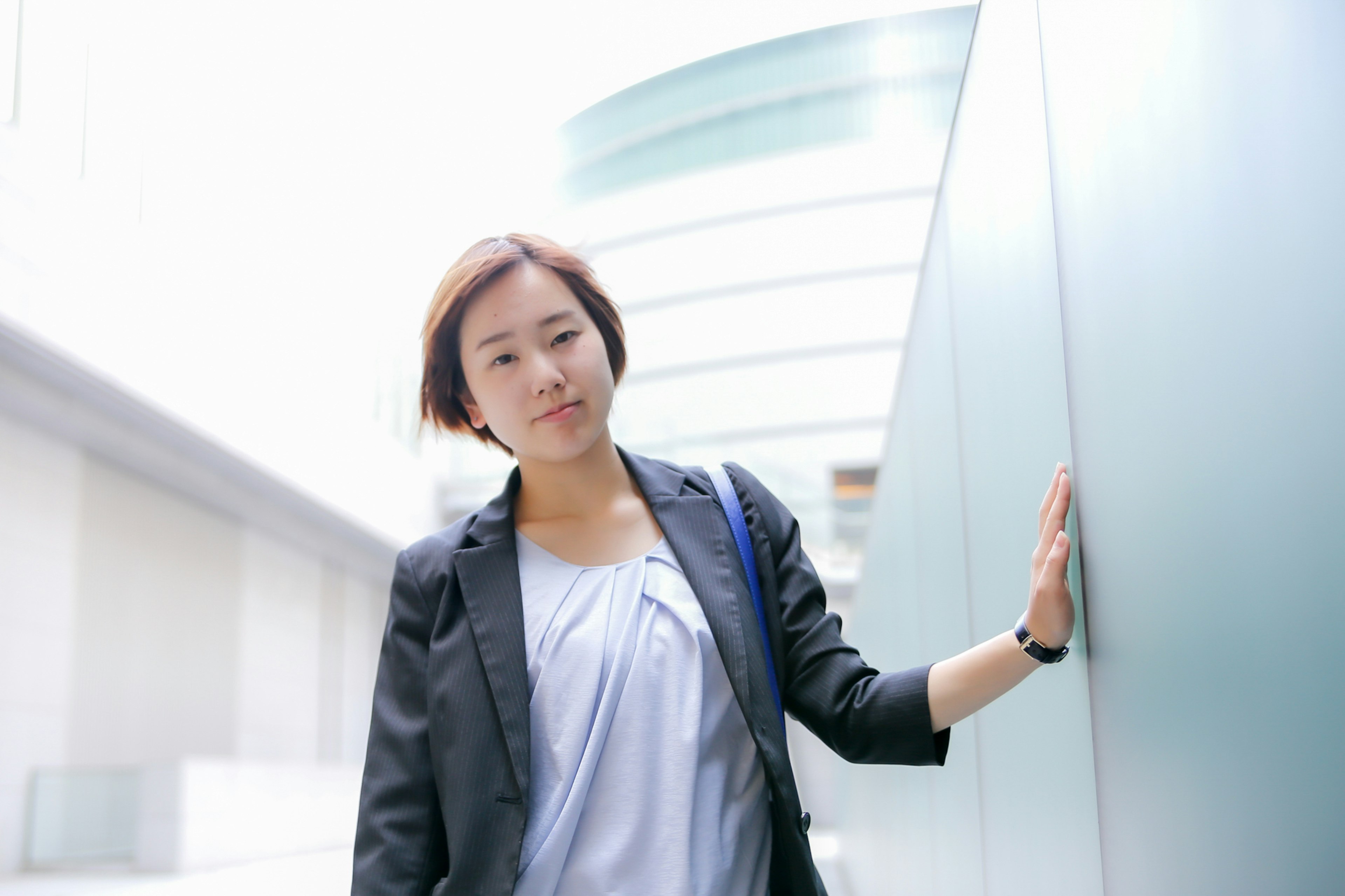 Une femme se tenant dans un bâtiment moderne touchant un mur