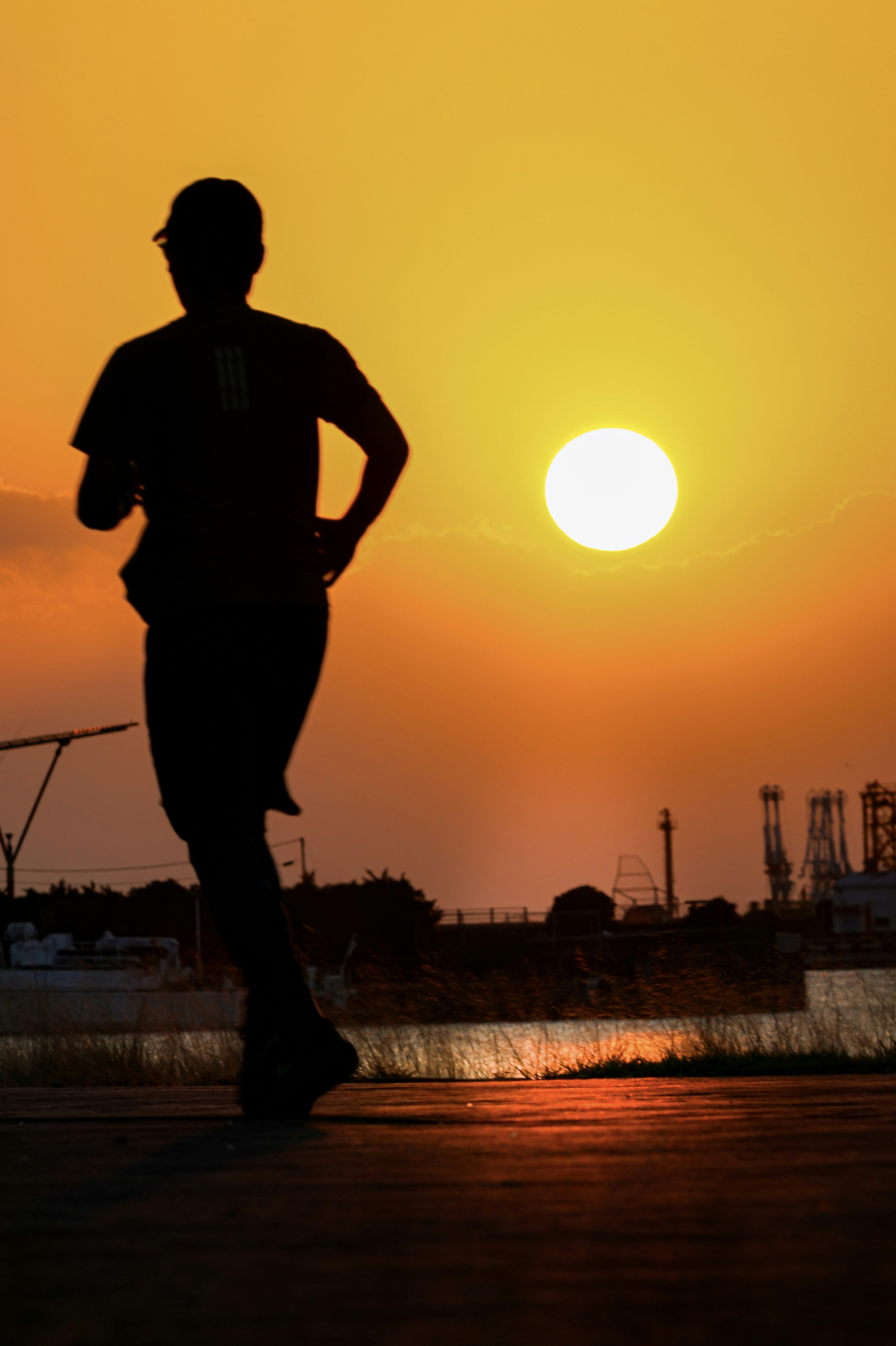 夕日をバックにランニングする人のシルエット