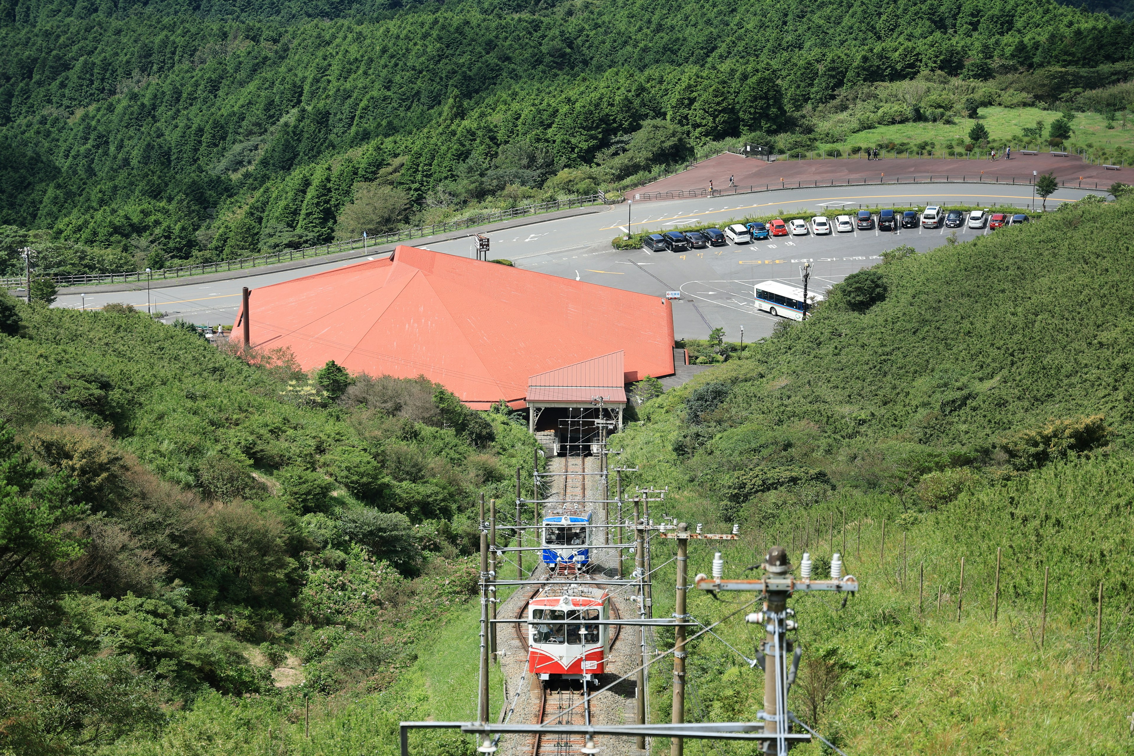 緑豊かな山の中にある赤い屋根の駅と列車