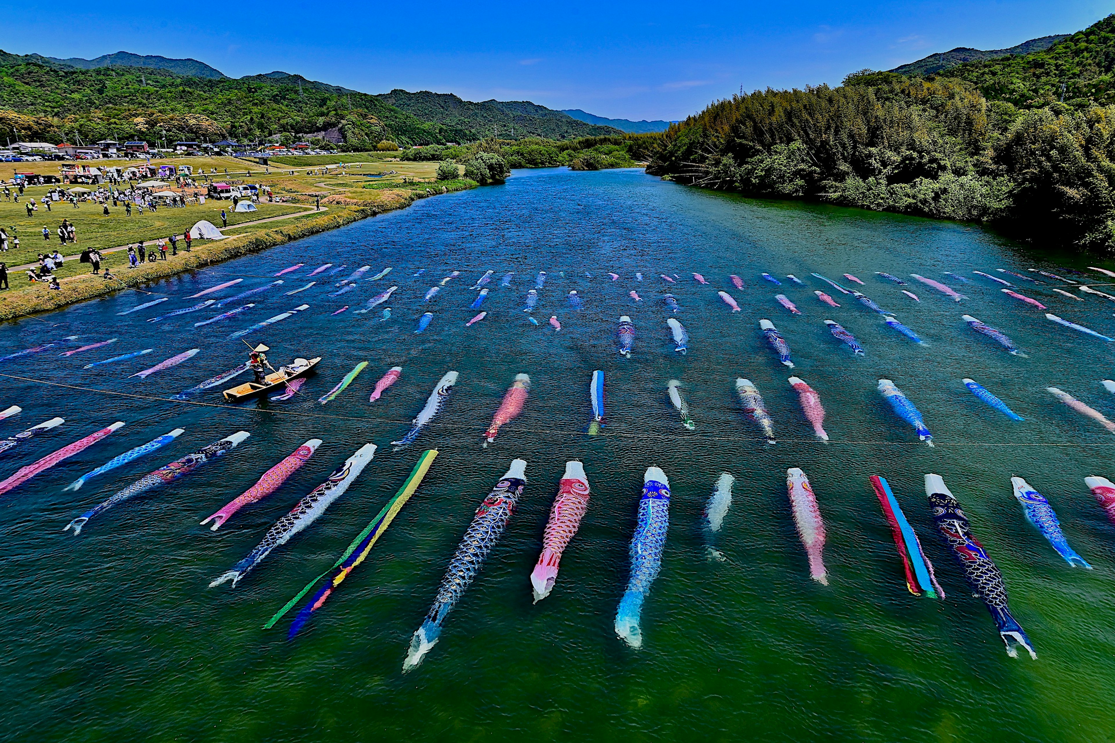 Colorful traditional fishing gear floating in a blue river with a person working in a small boat