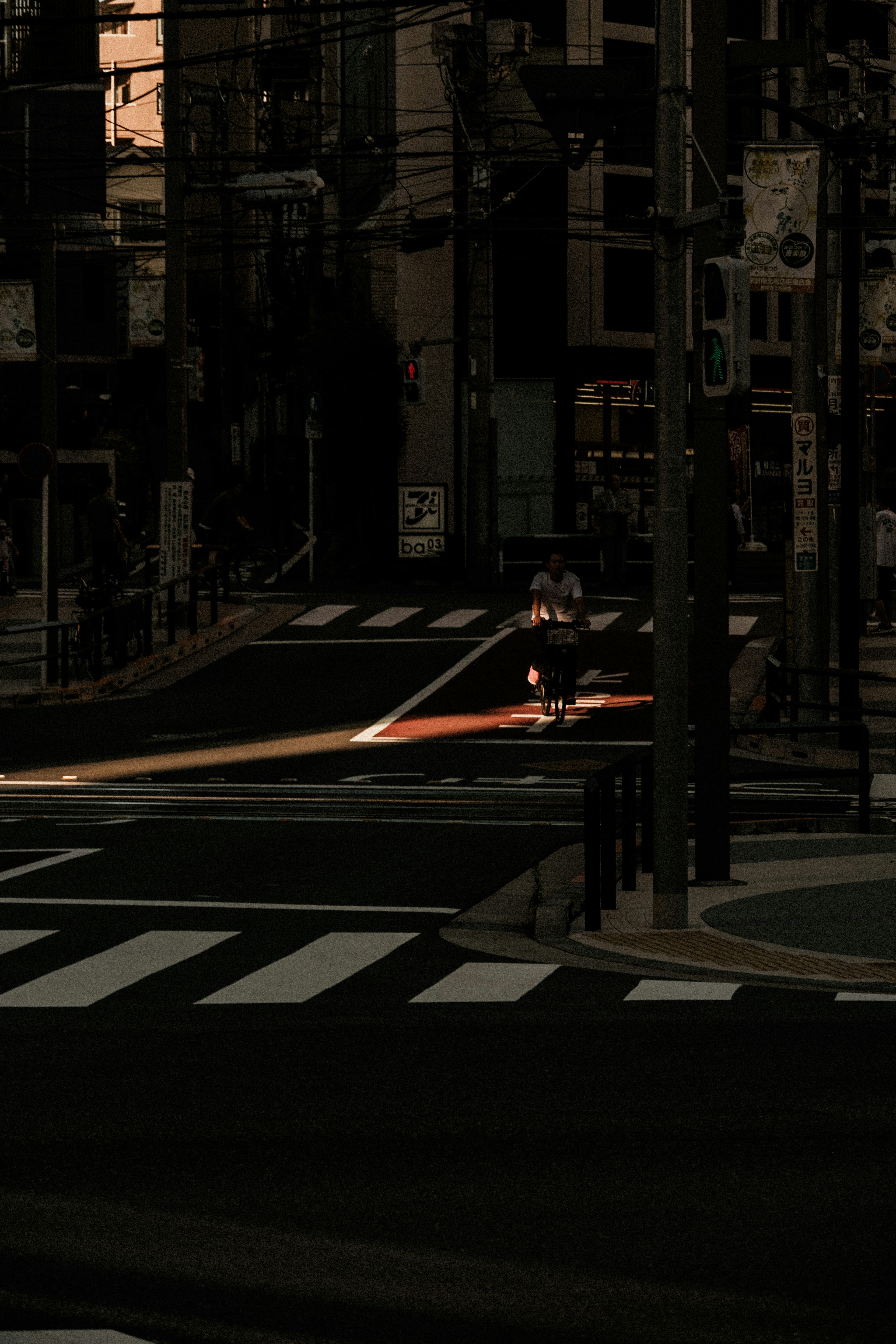 Silhouetted figure at a dimly lit intersection with a glowing red signal