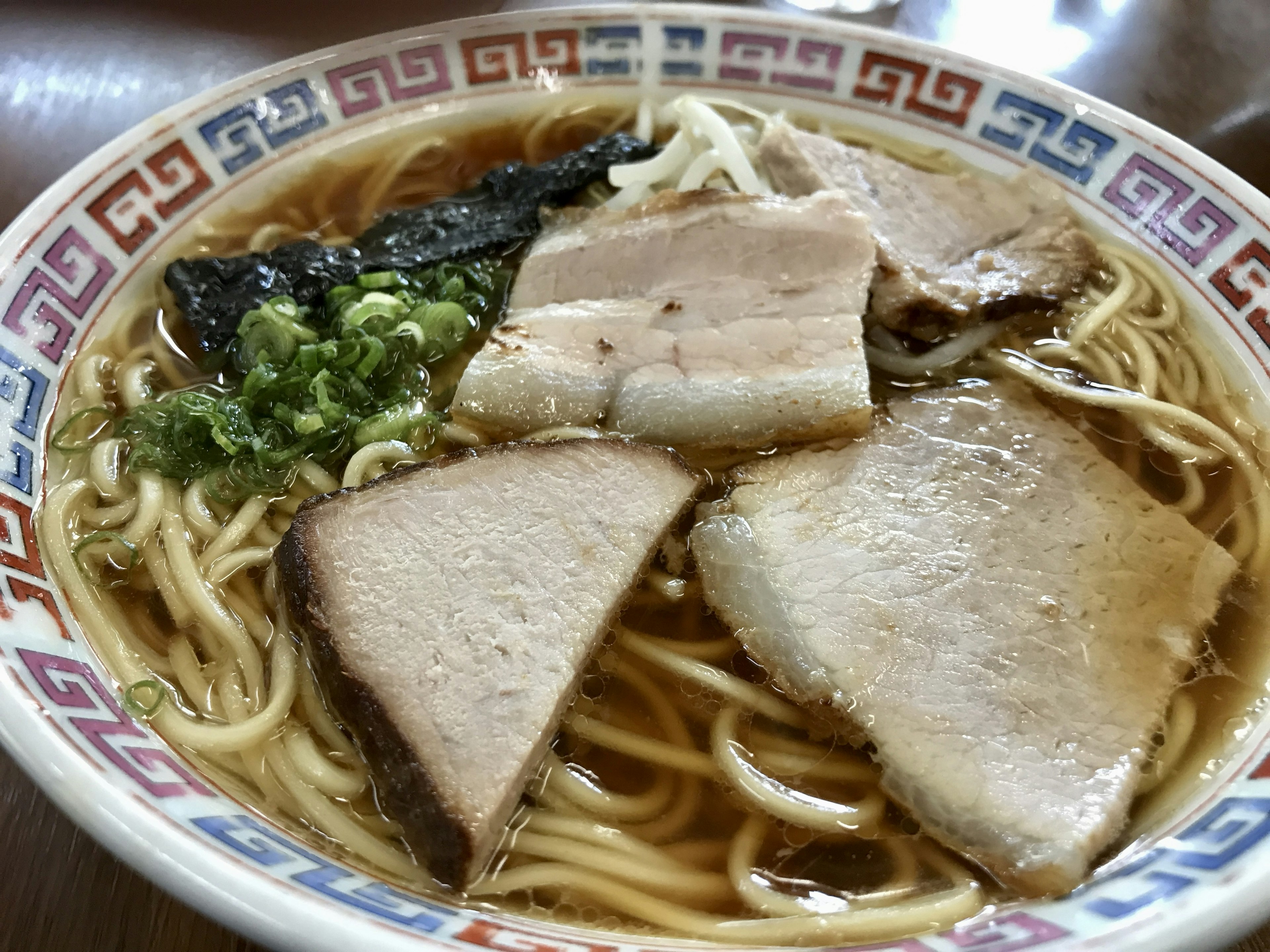 美味しそうなラーメンの皿にチャーシュー、ネギ、海苔がのっている