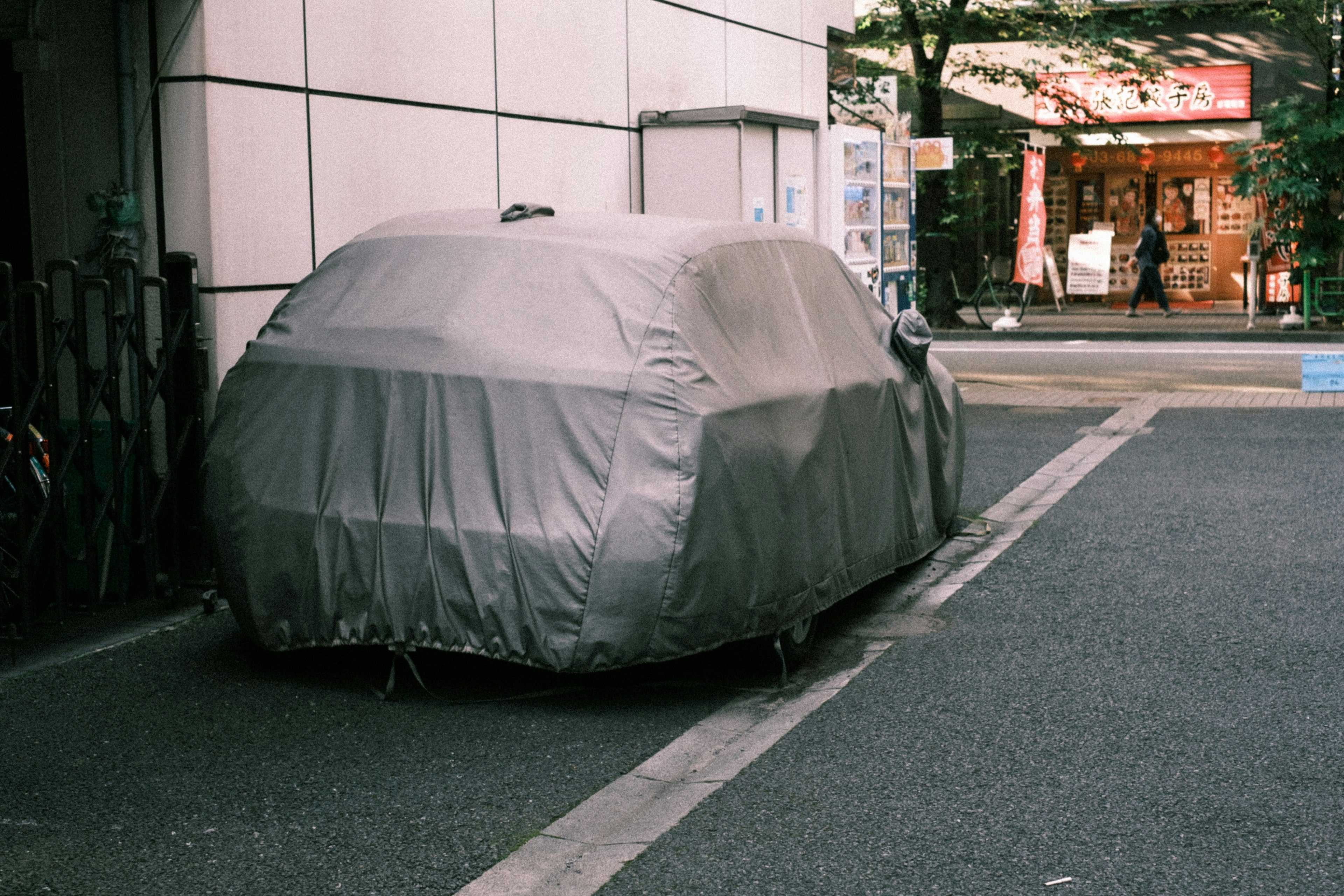 A car covered with a protective cover parked on the street