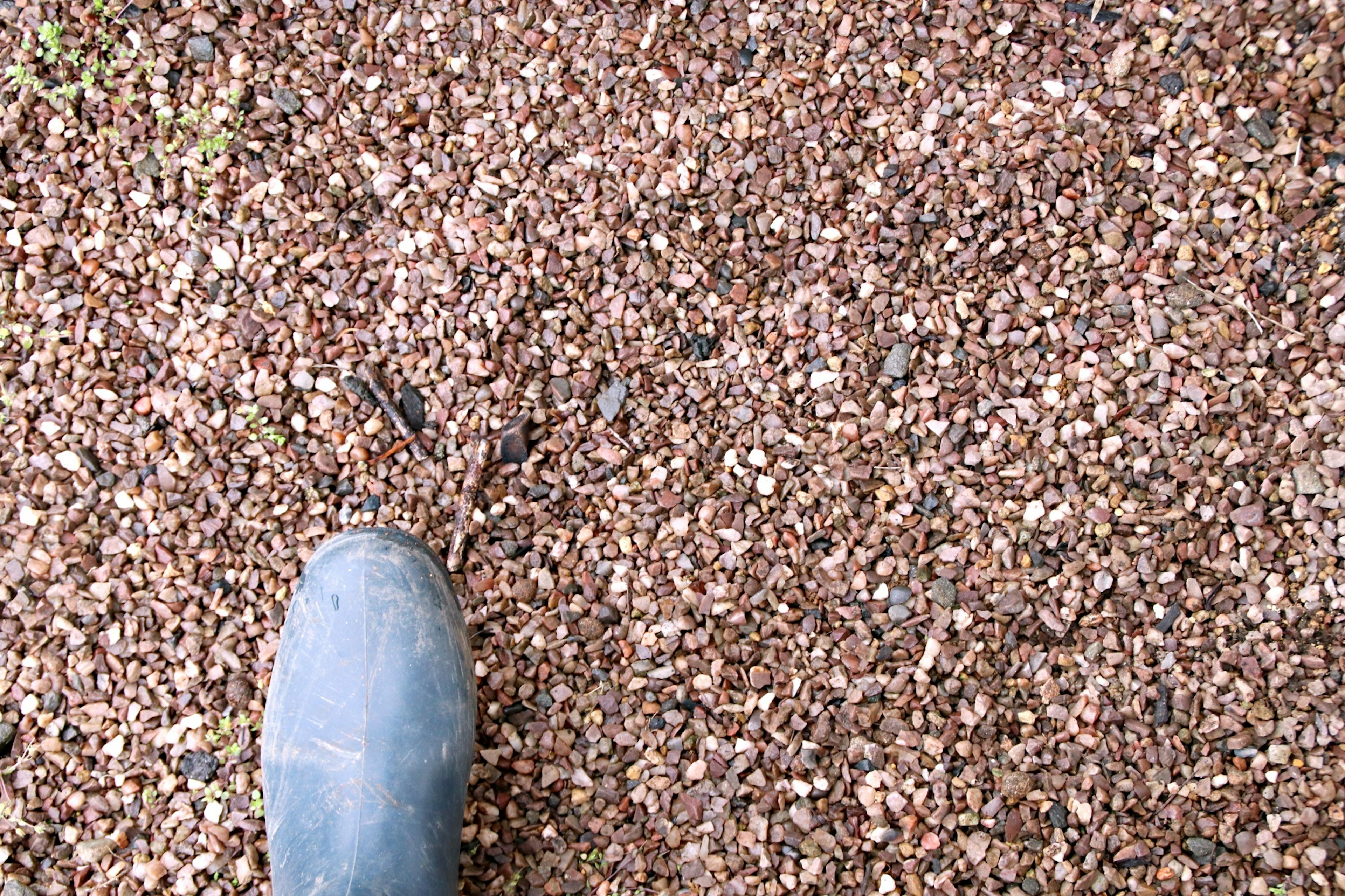 Close-up of a boot standing on gravel surface