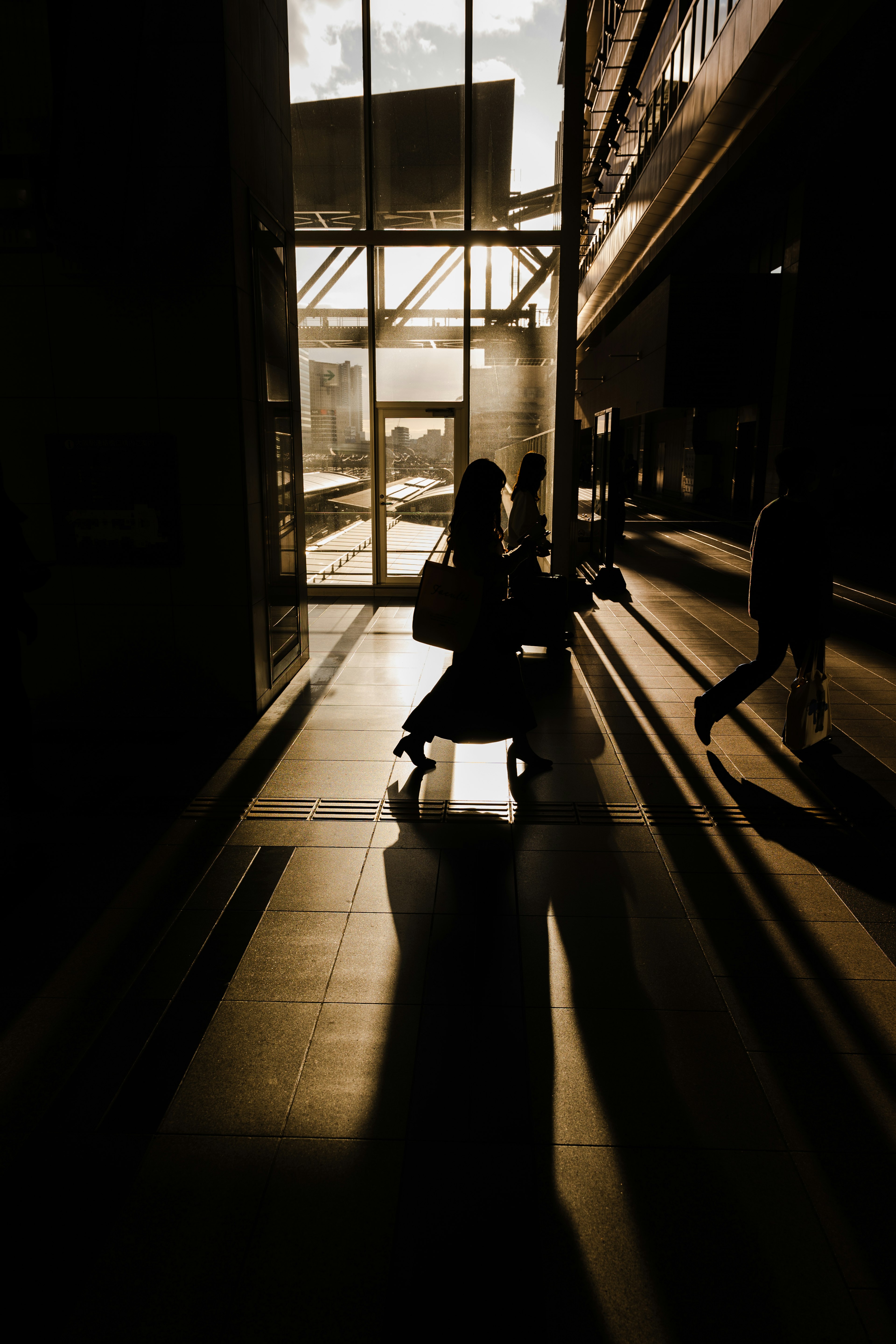 Silhouetted people walking in a building with sunset backdrop