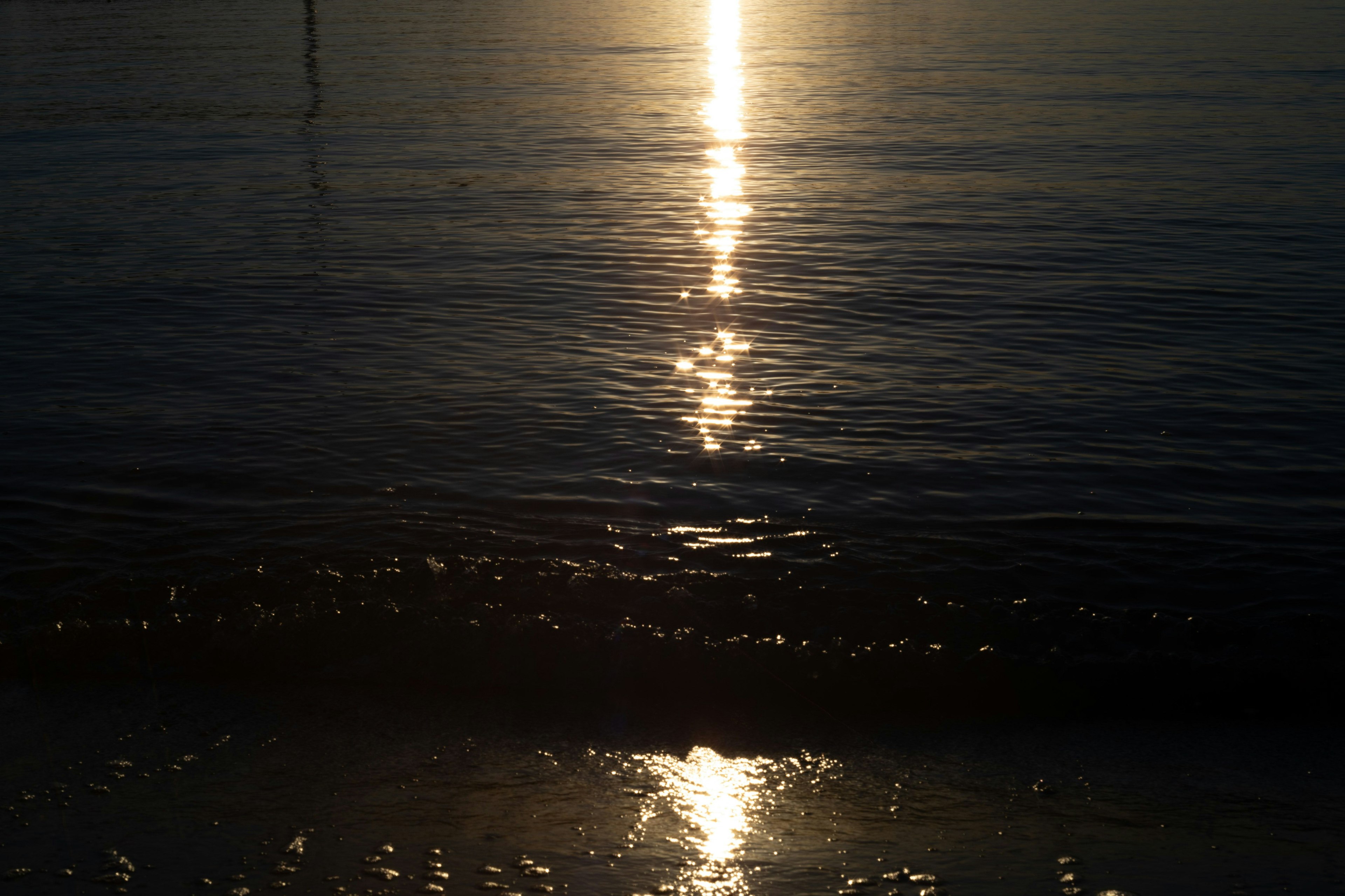 海の上に反射する夕日の光と穏やかな波