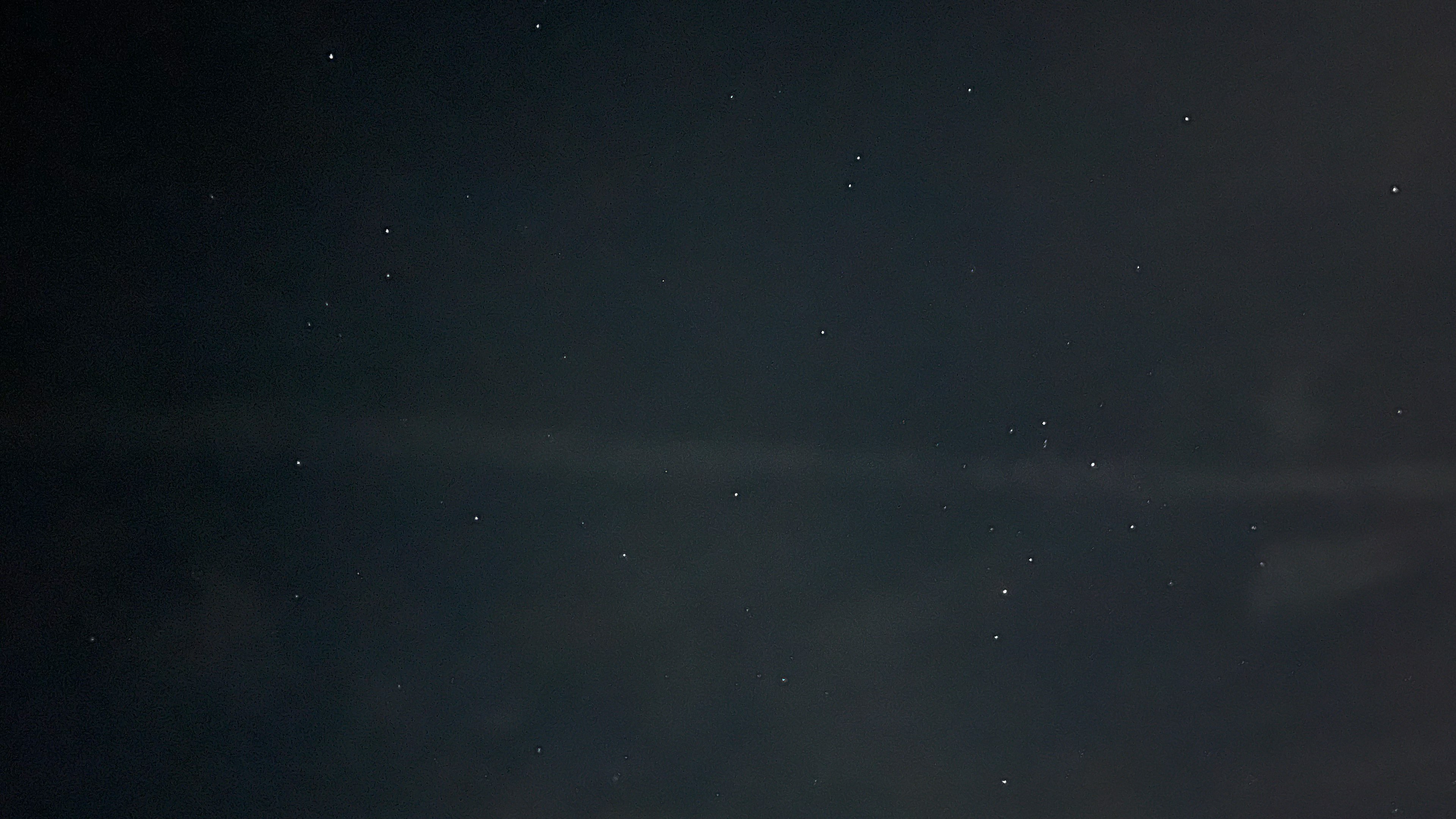 Un ciel étoilé avec de petits points lumineux éparpillés sur un fond sombre