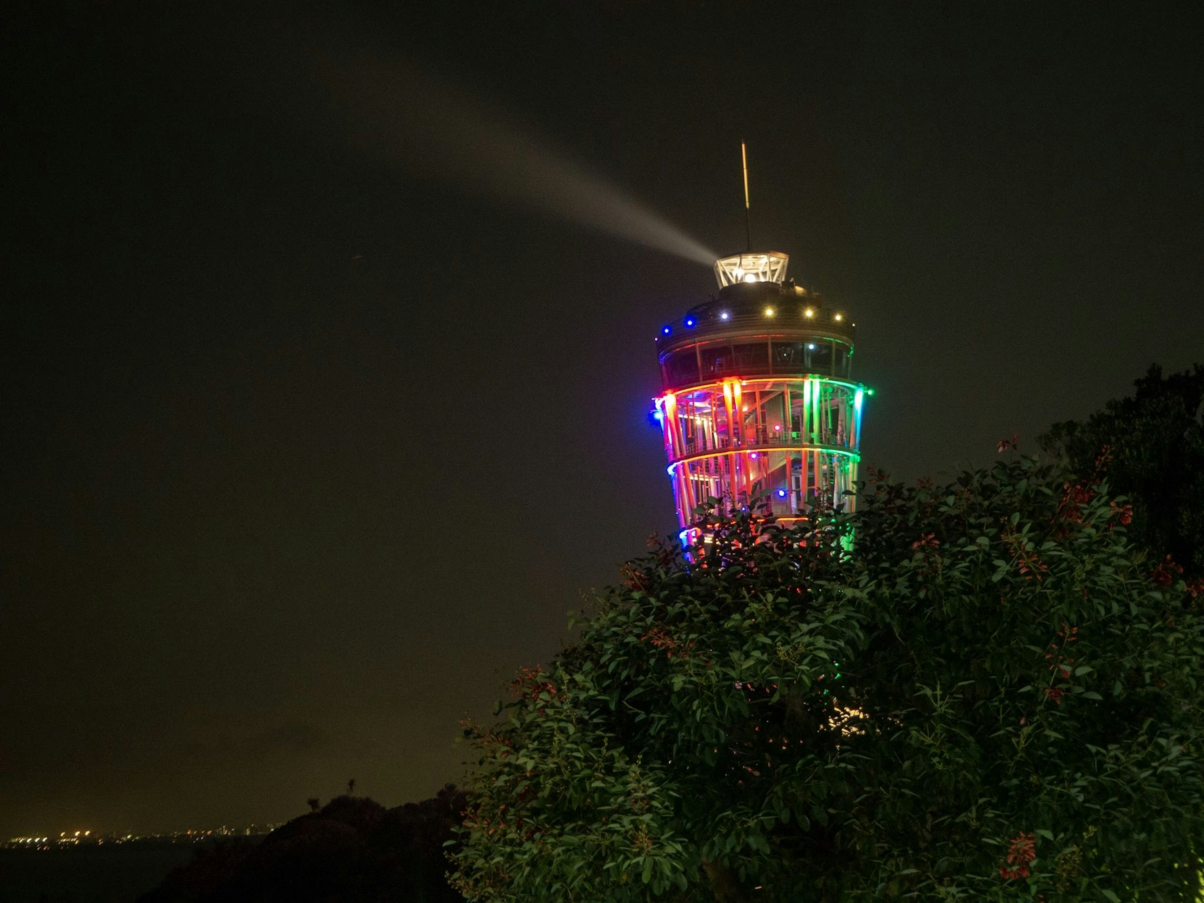 Tour illuminée colorée la nuit entourée de verdure