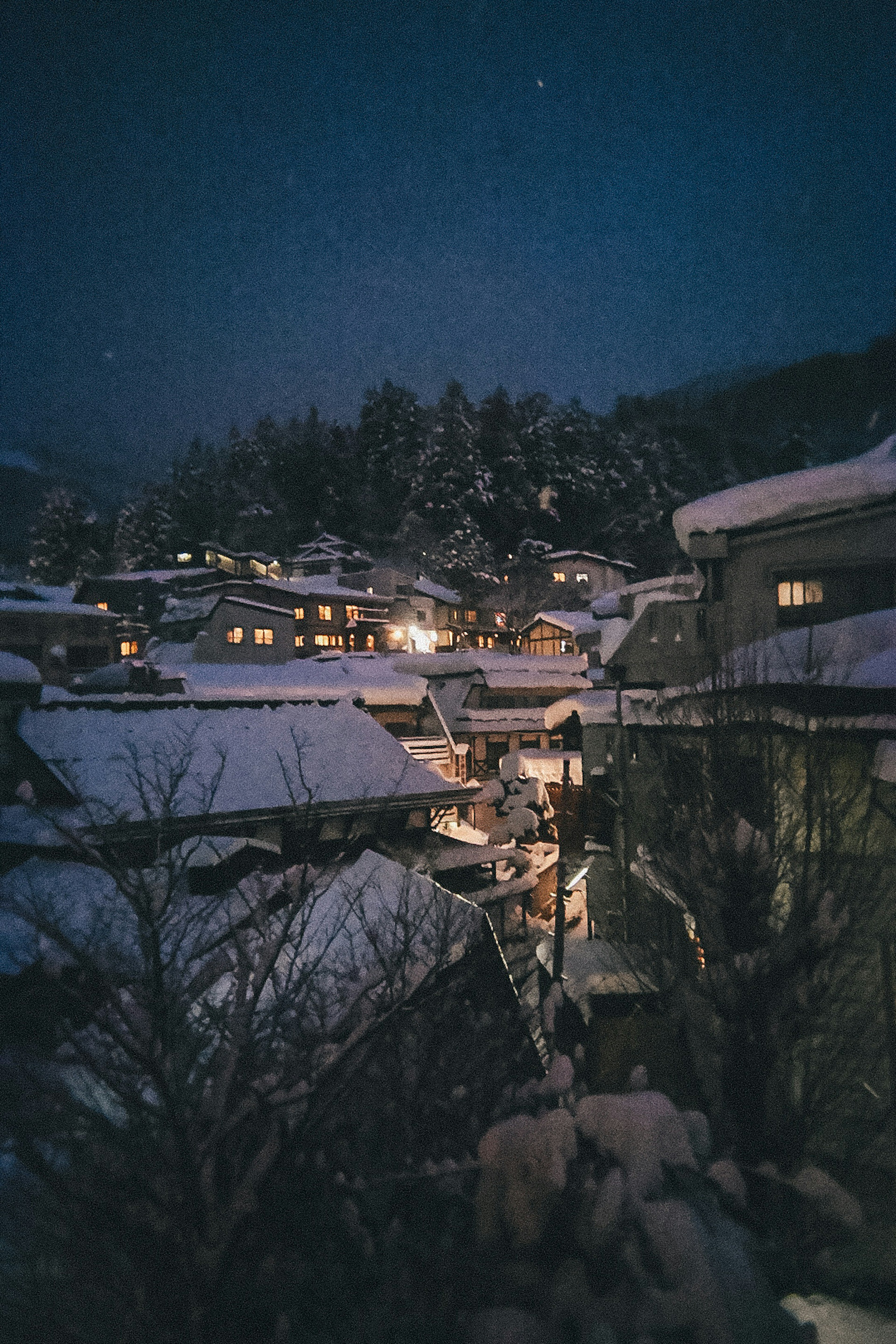 Pueblo cubierto de nieve por la noche con casas iluminadas y paisaje sereno