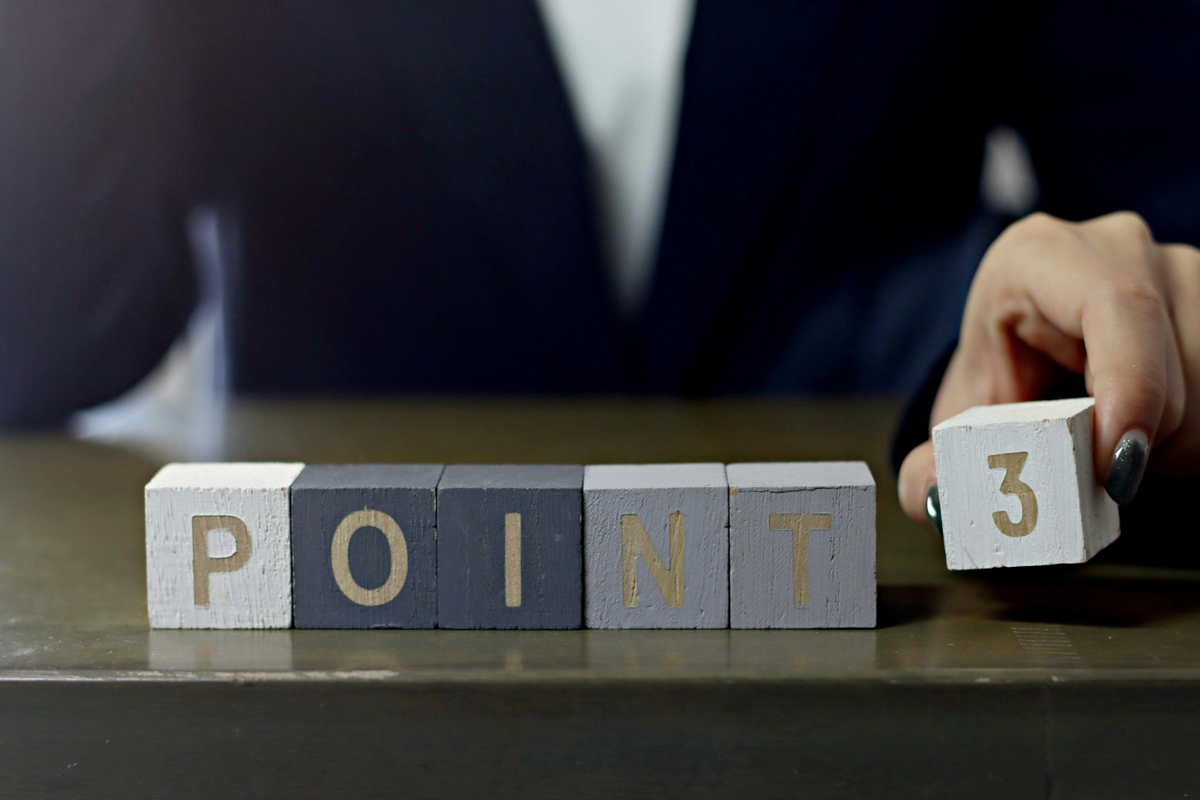 A hand in a business suit holding a block marked with POINT 3