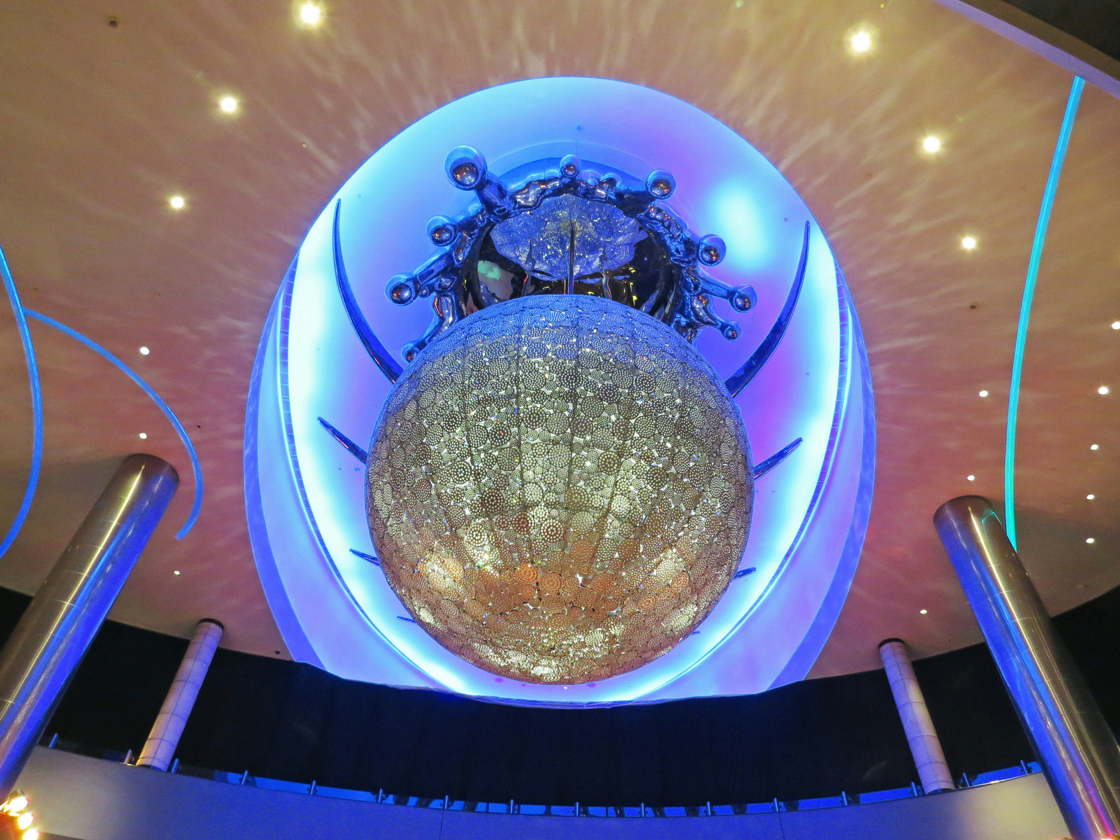 Large spherical structure illuminated by blue and purple lights hanging from the ceiling