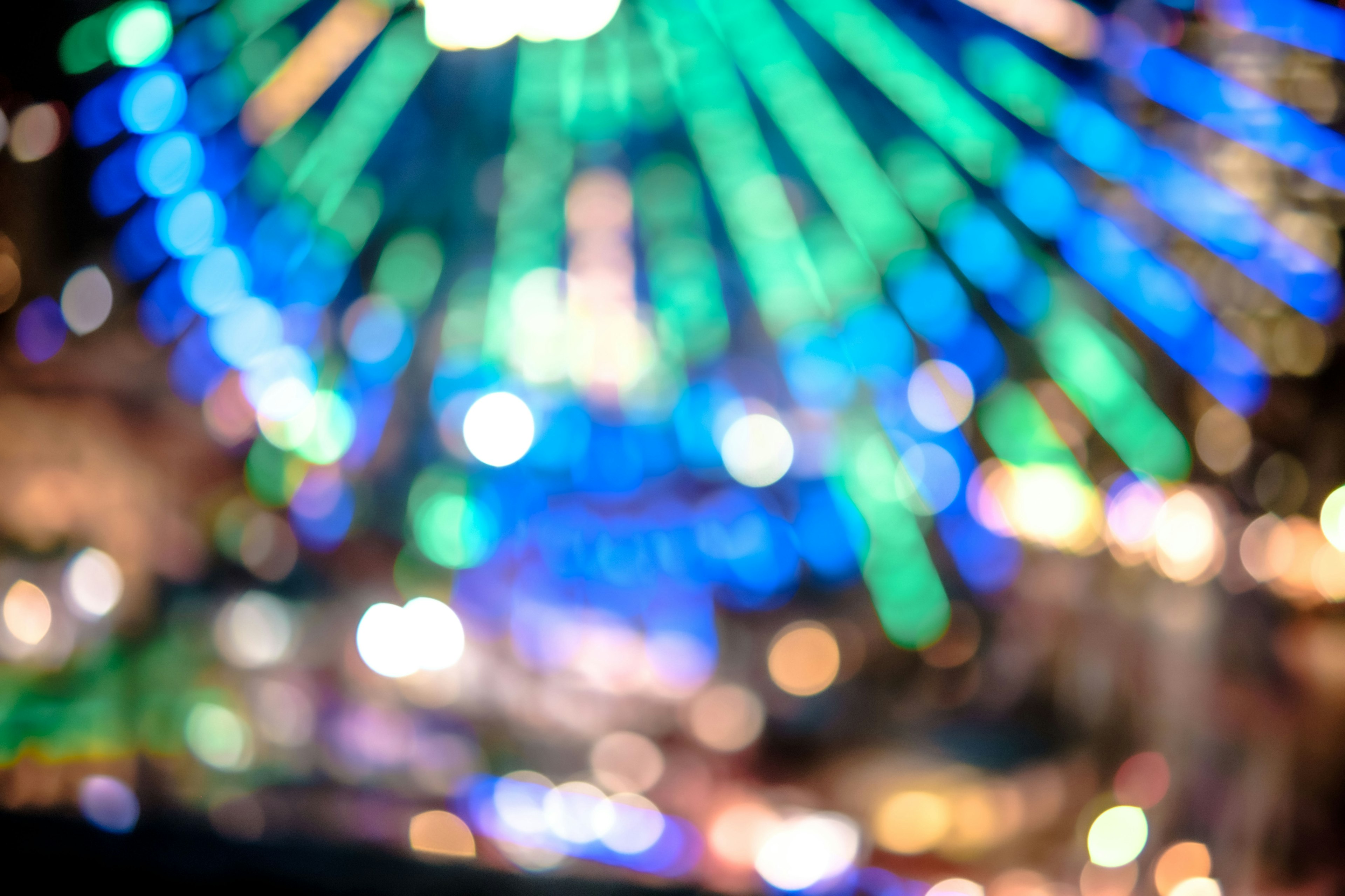 Image floue d'une grande roue colorée avec des lumières bleues et vertes vives