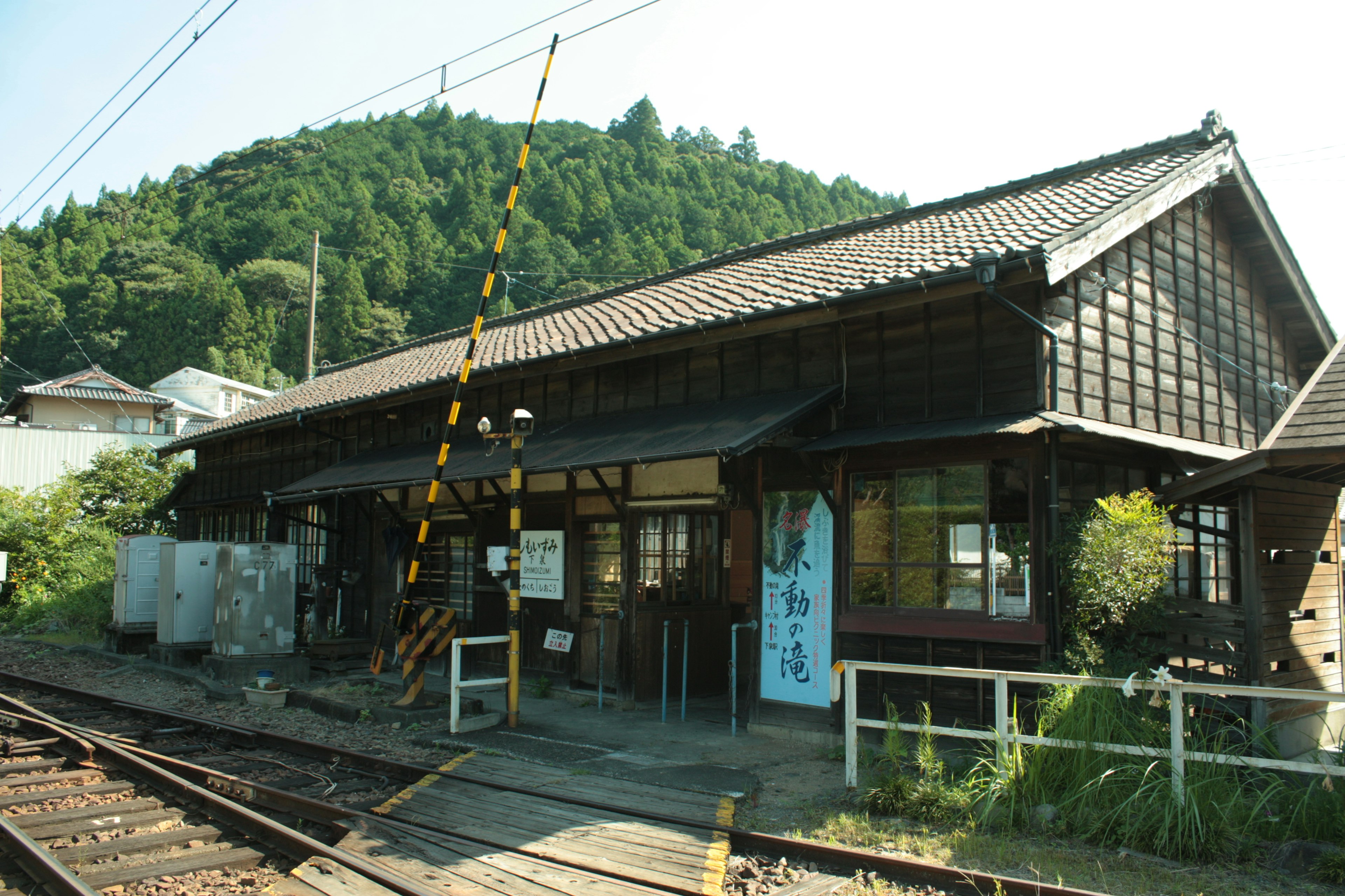 古い木造の駅舎と緑豊かな山の背景