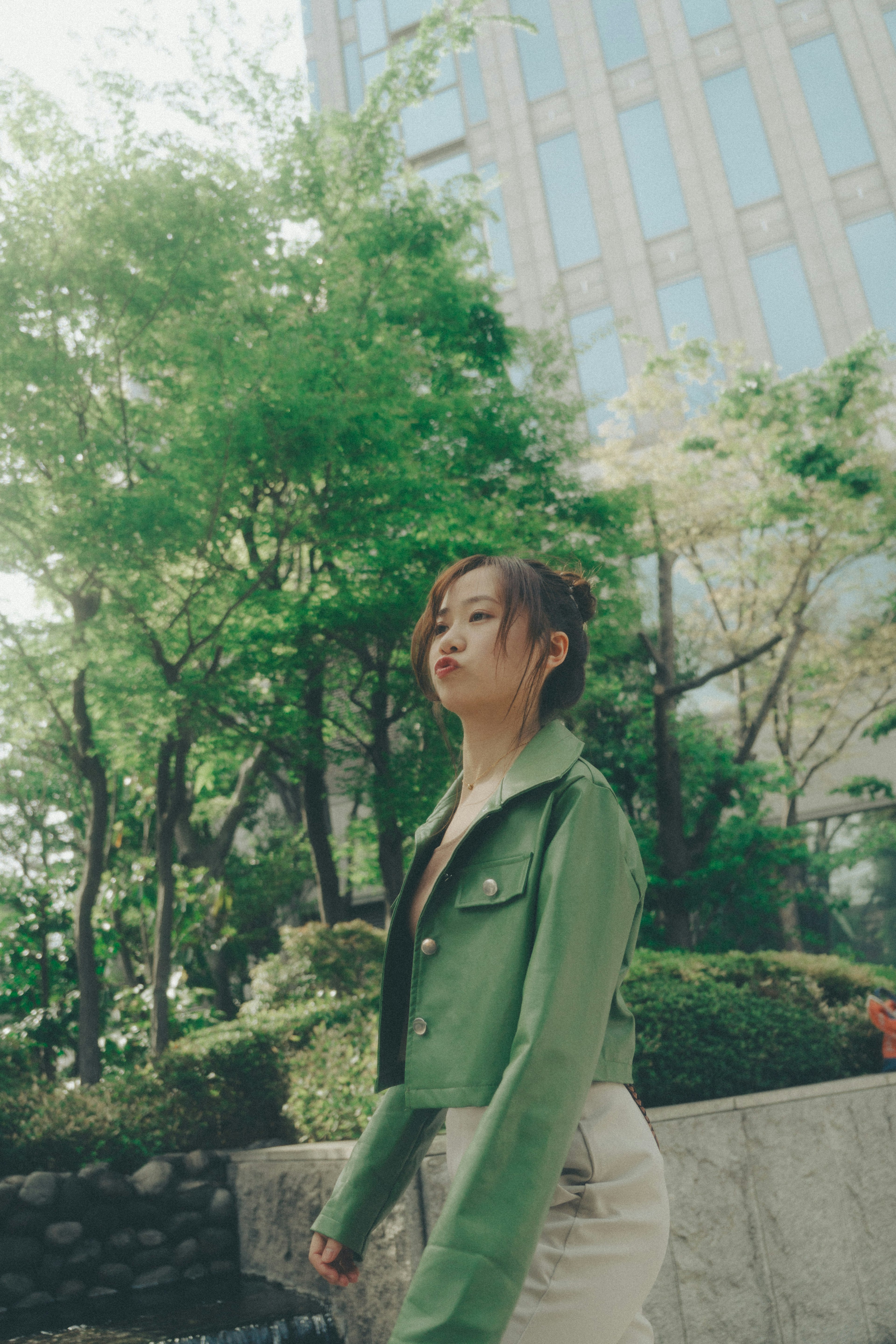 Woman in green jacket walking in a park with trees