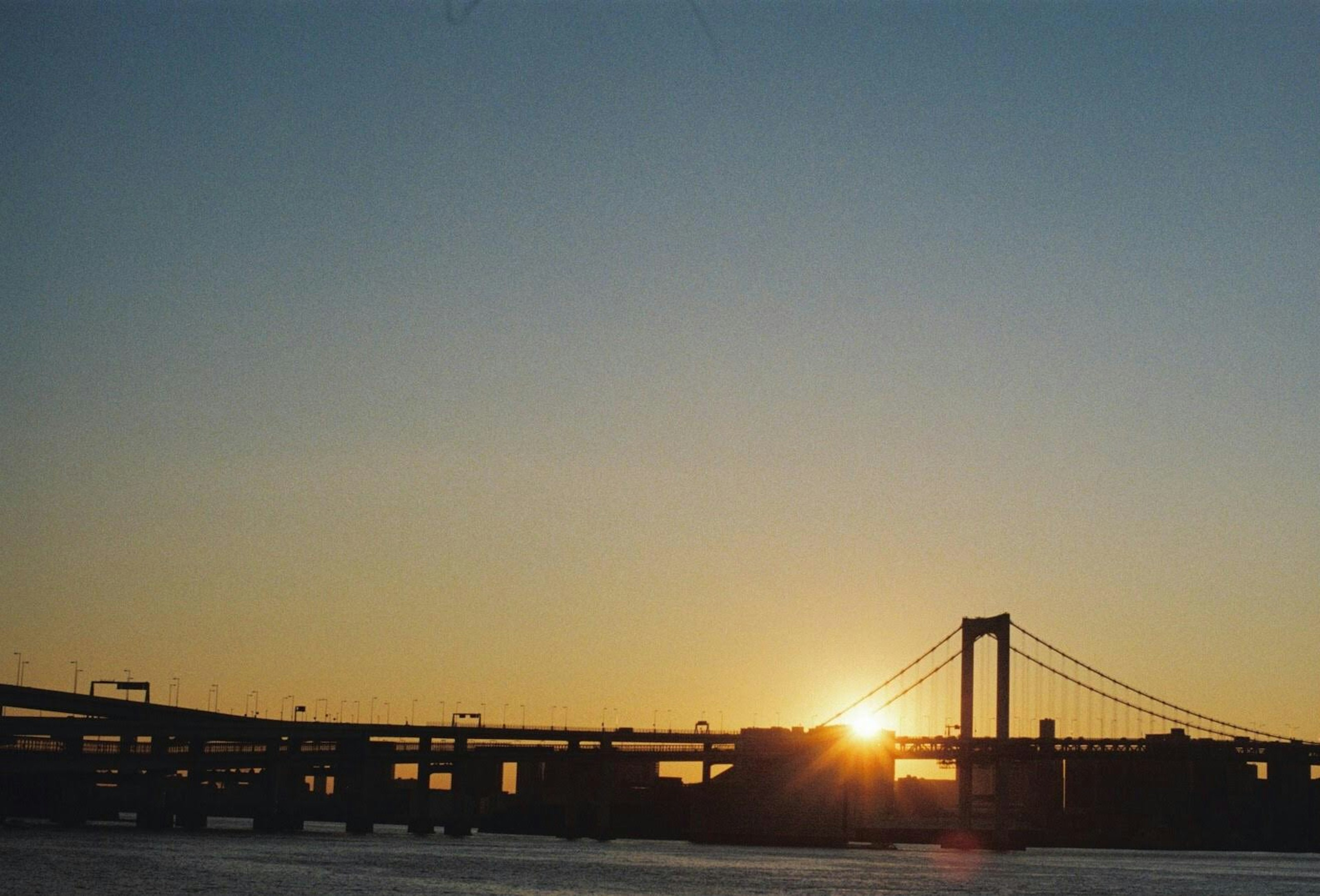 Atardecer detrás de un puente con cielo despejado