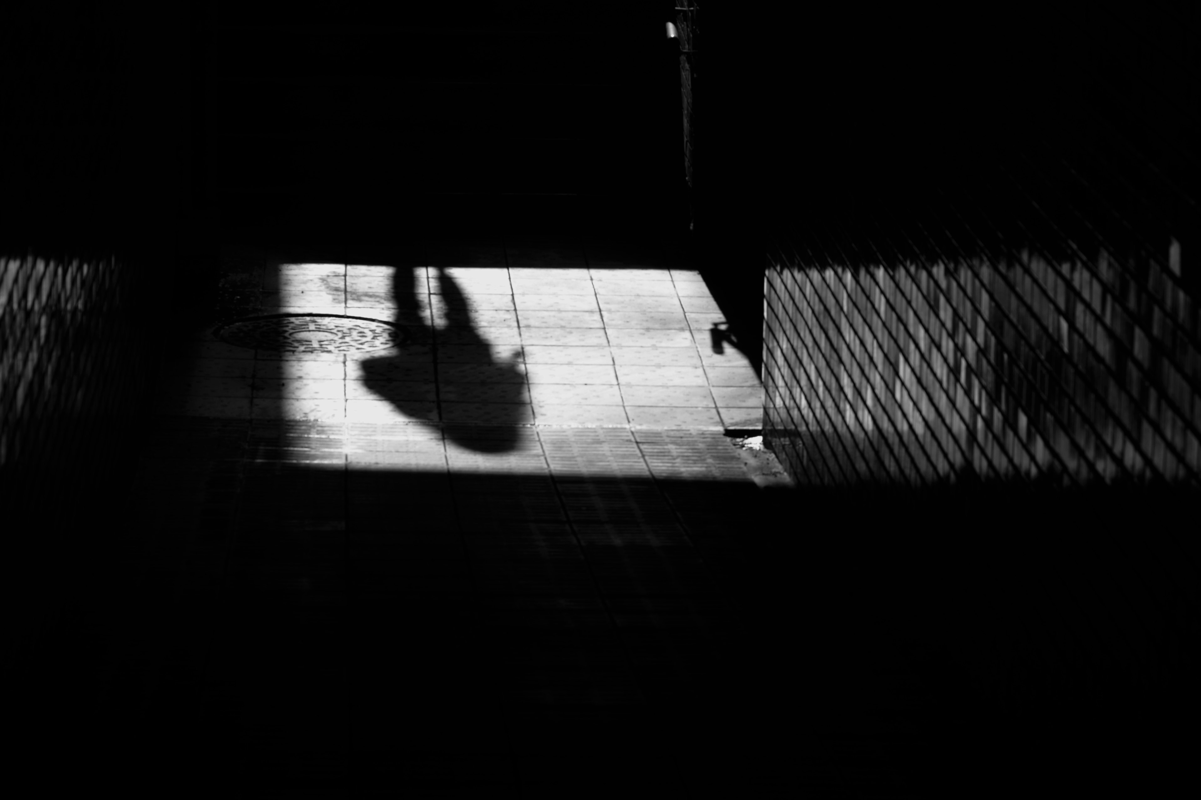 Schatten einer Person in einem dunklen Tunnel mit Bodenreflexionen