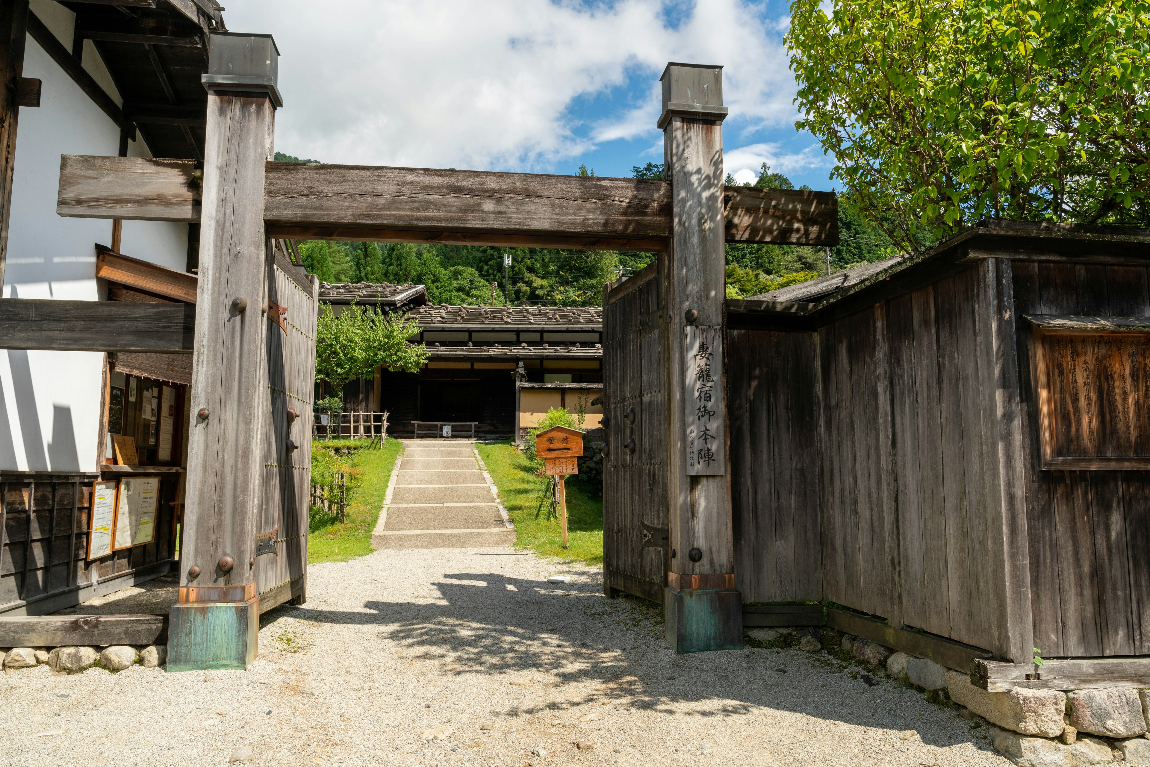 Porta giapponese tradizionale con un sentiero in pietra che conduce a un giardino