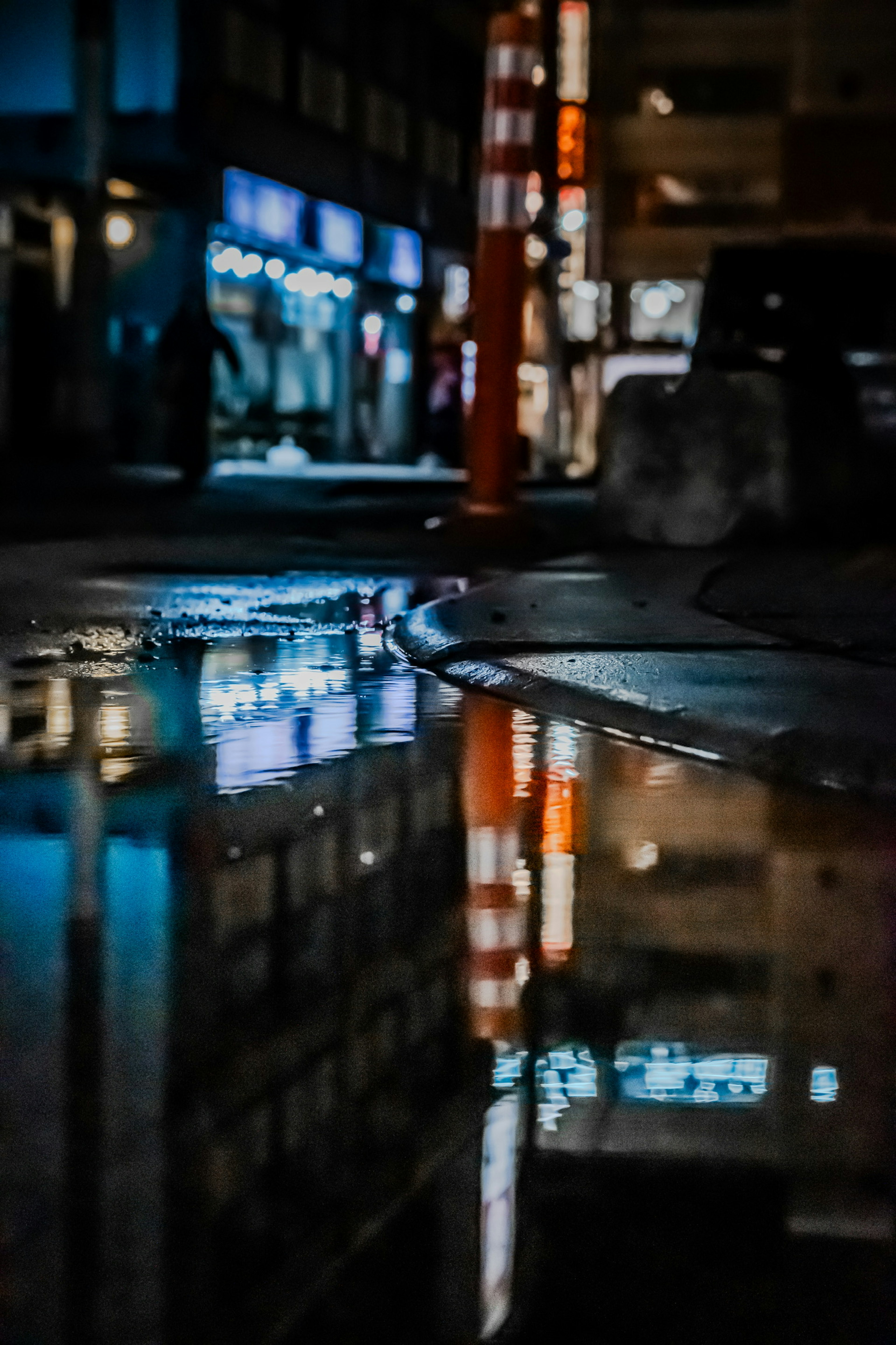 Puddle reflecting neon lights and buildings in a nighttime urban setting