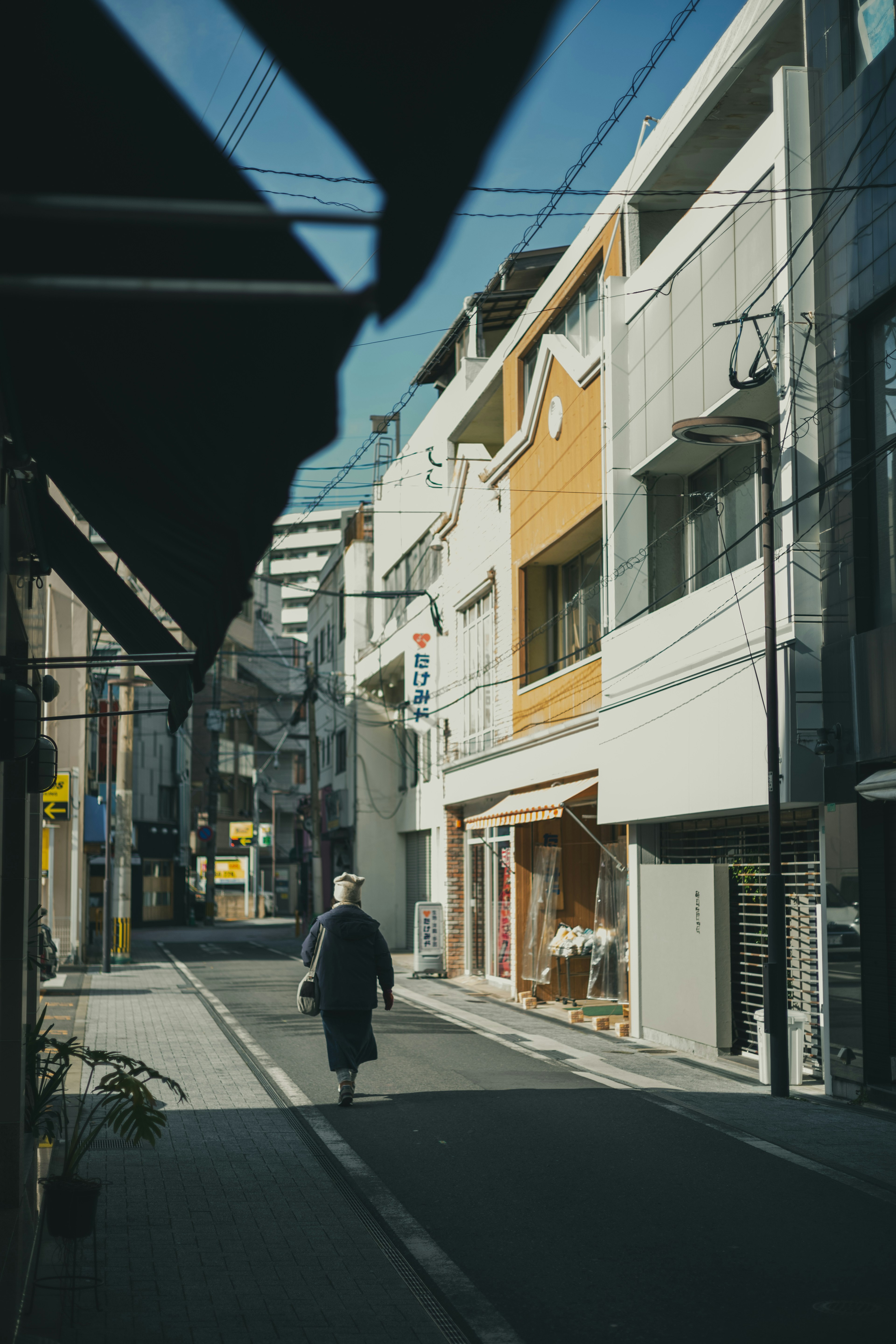 Una persona mayor caminando por una calle tranquila con edificios modernos