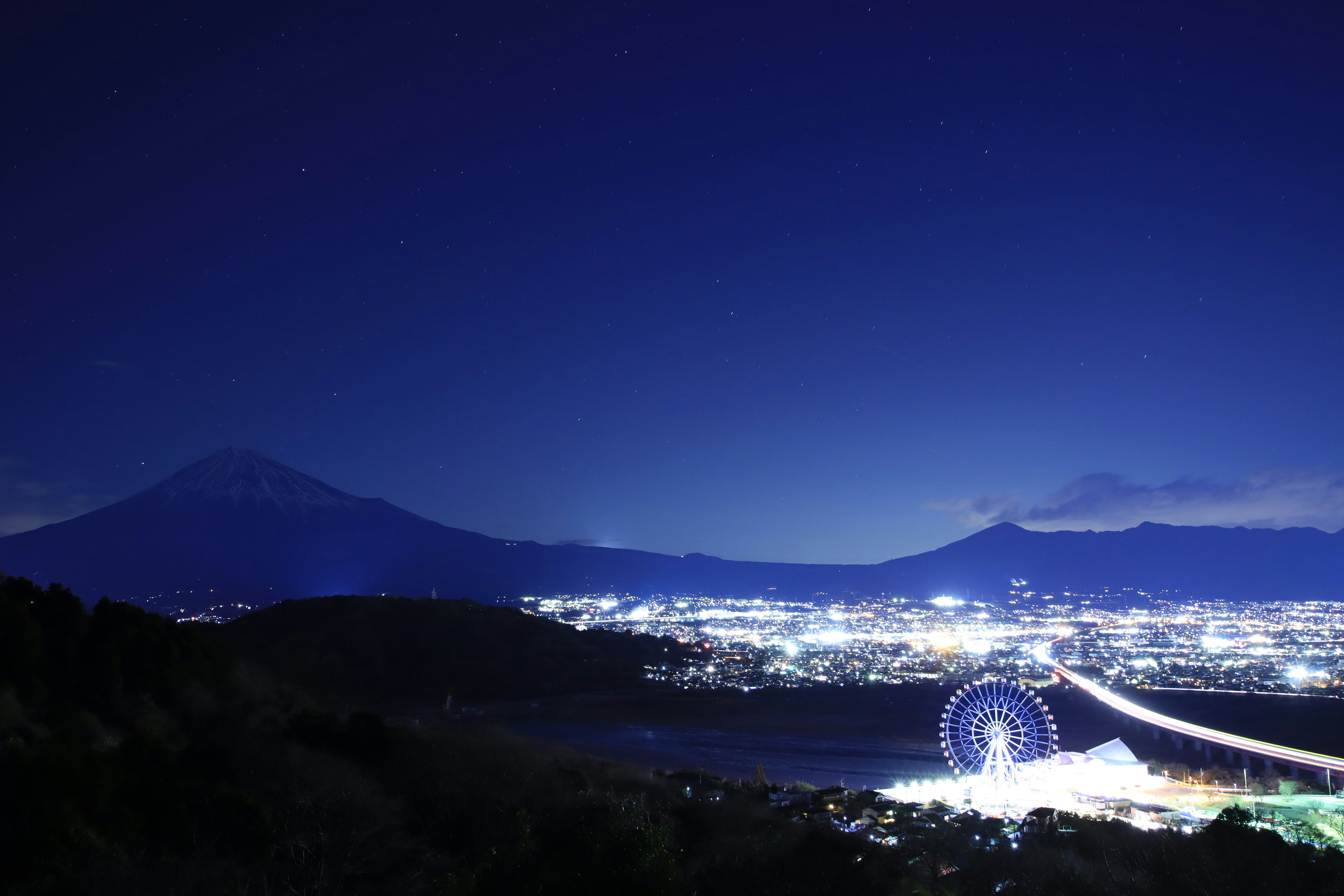 Night view of Mount Fuji and a Ferris wheel overlooking the city