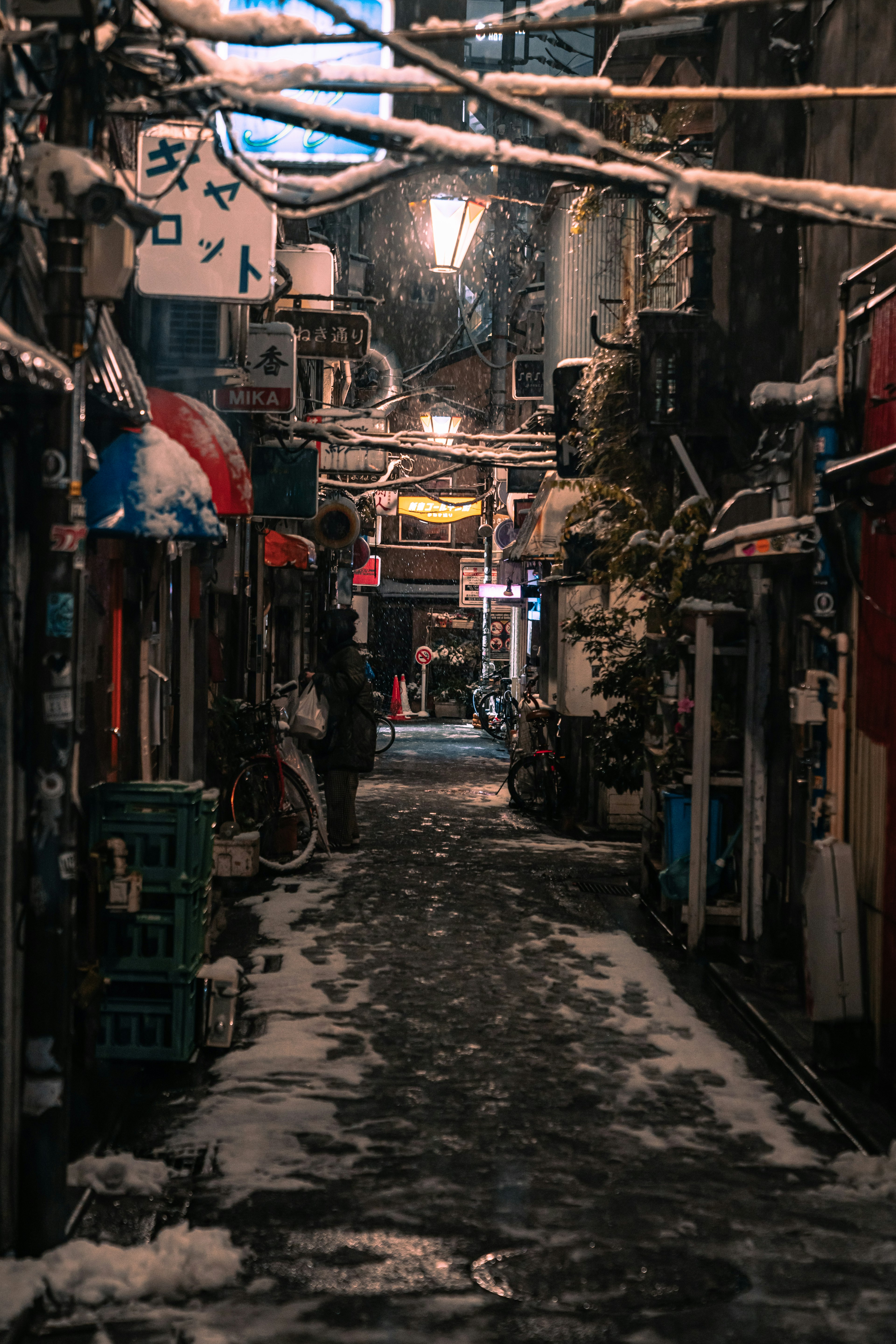 Narrow alleyway covered in snow with streetlights at night