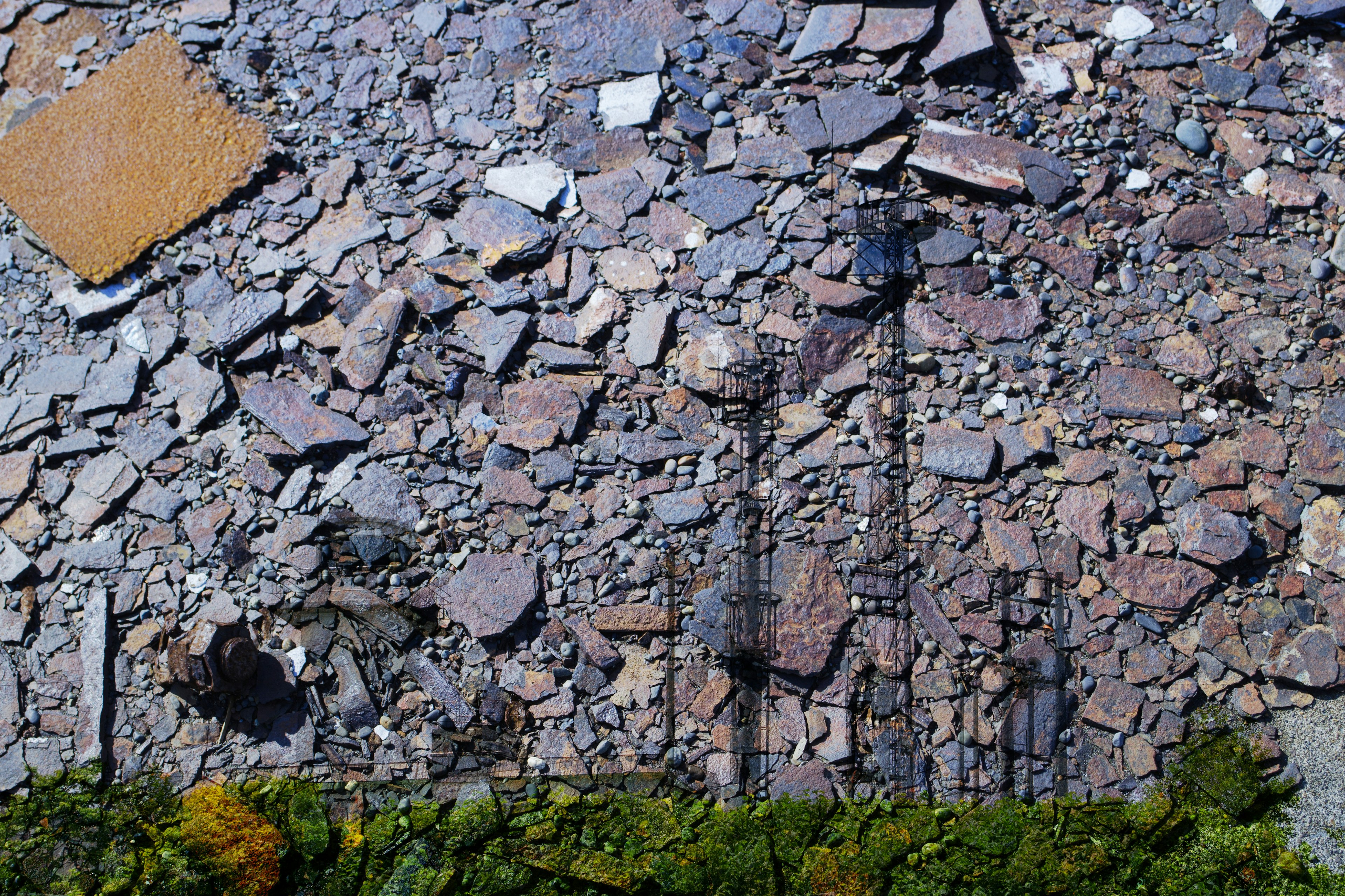 Textured ground covered with stones and rocks with green vegetation