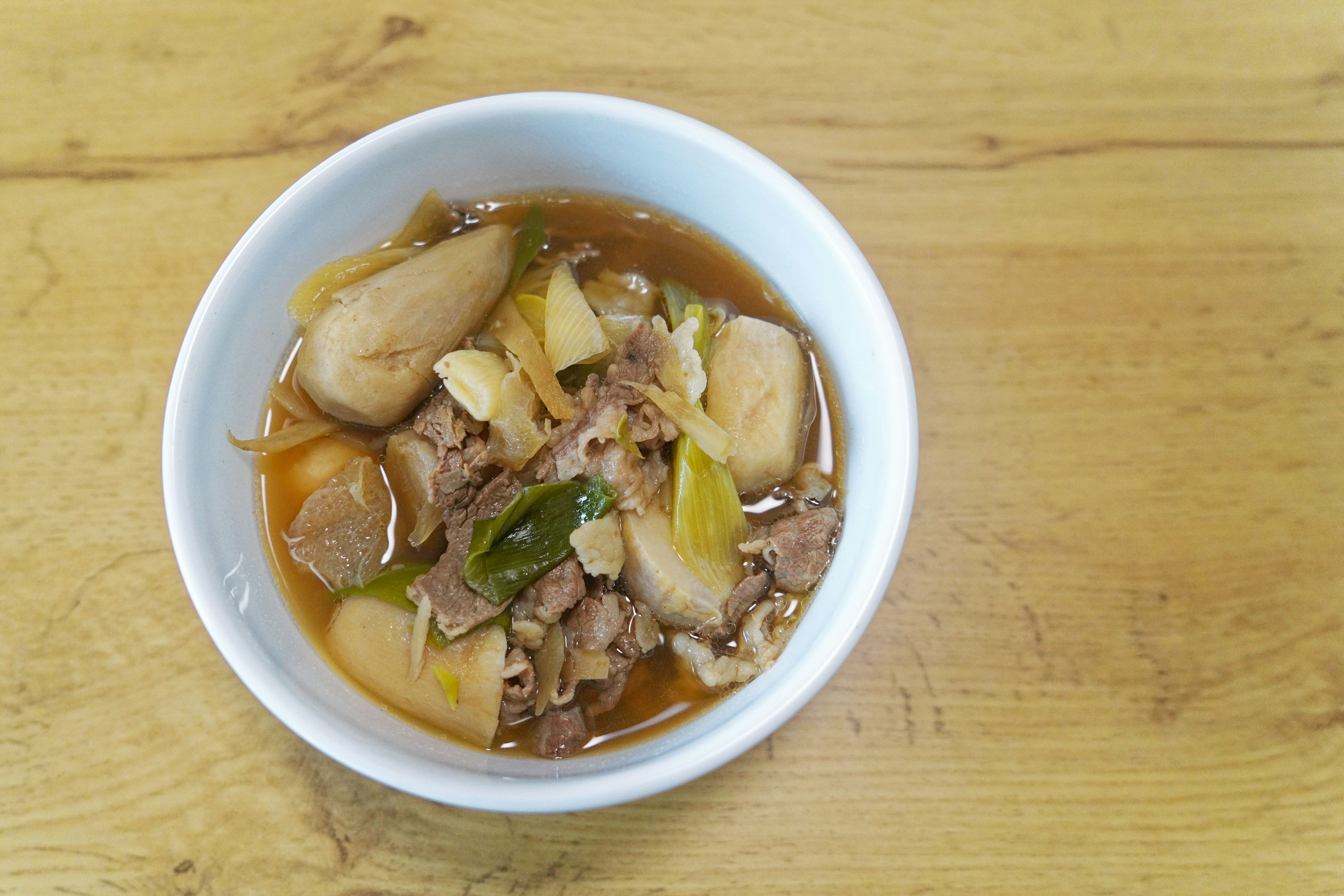 Bol de soupe de viande et de légumes sur une table en bois