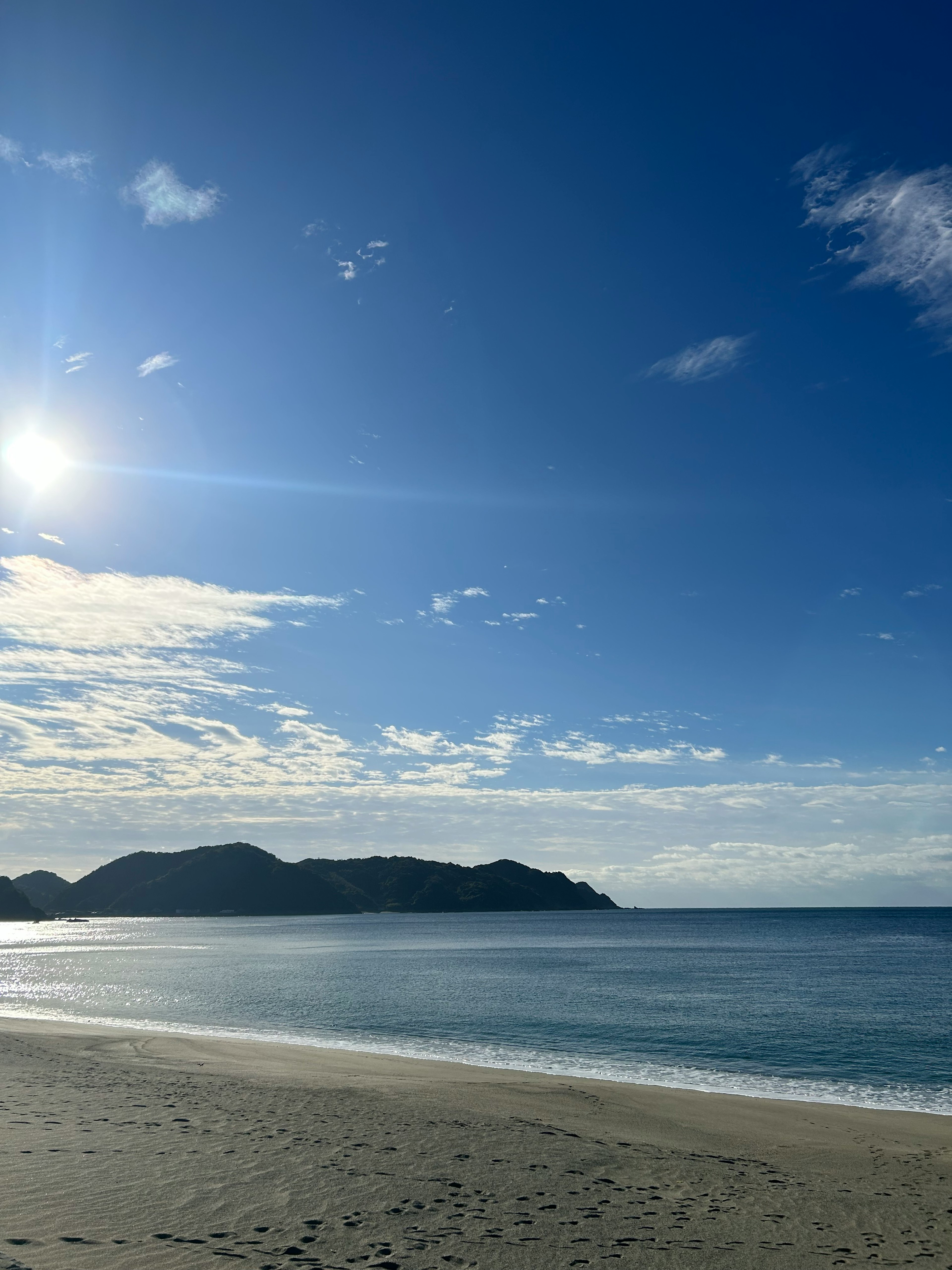 Scenic beach view with a blue sky and calm ocean sunlight shining