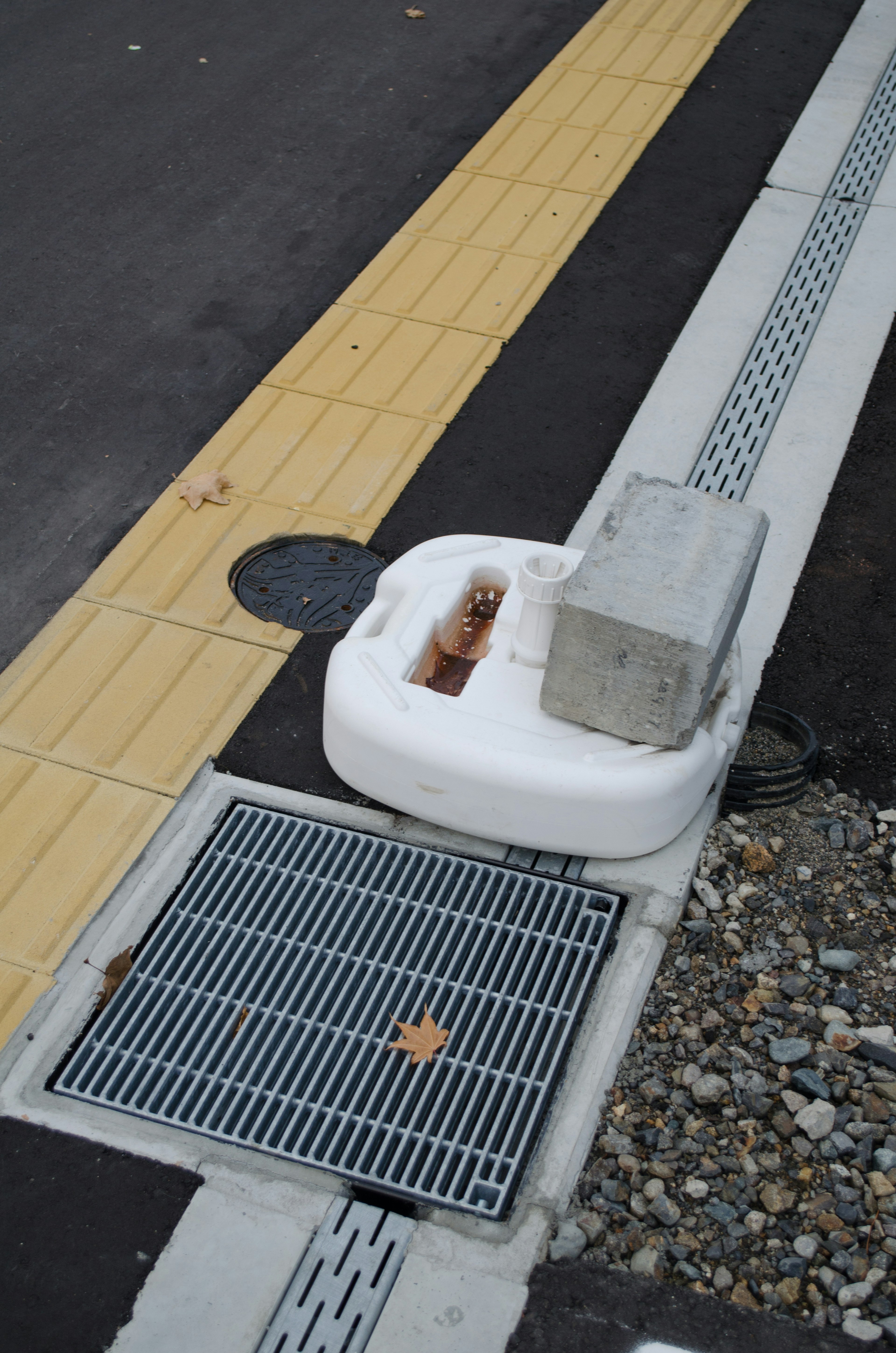 White drainage outlet and gray cover on the roadside