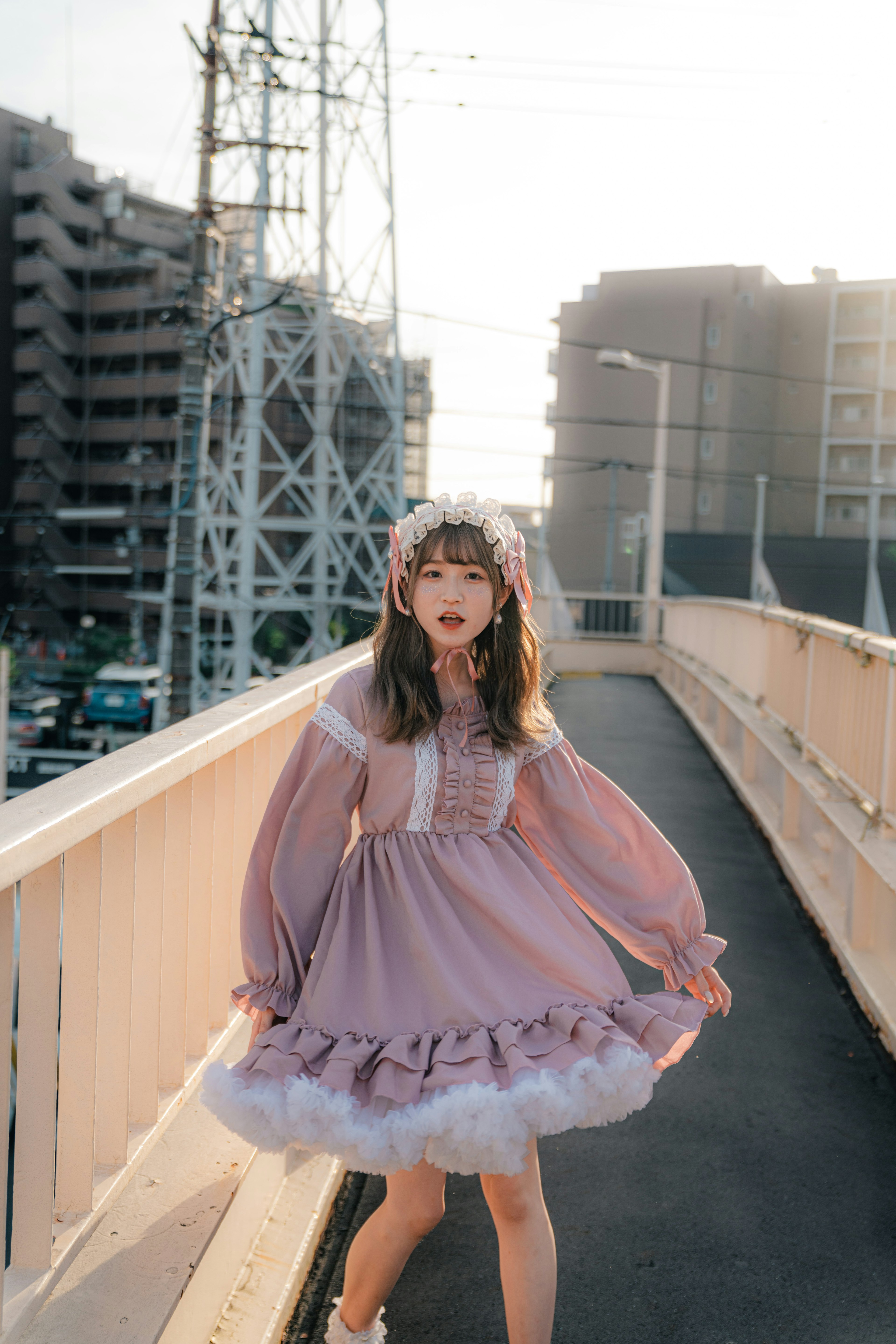 Une femme en robe rose posant sur un pont urbain