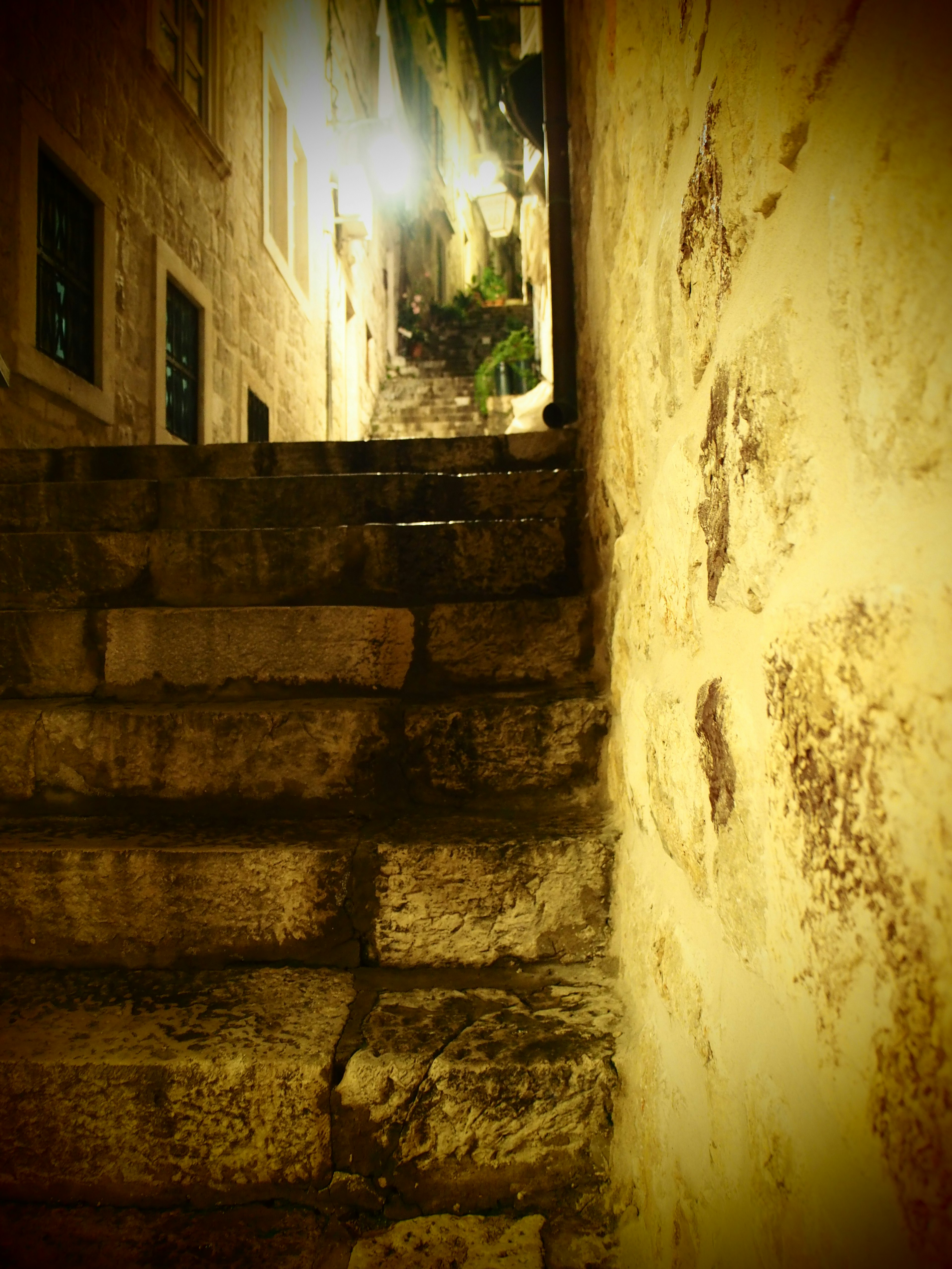 Image of old stone stairs and wall with a glimpse of a bright street